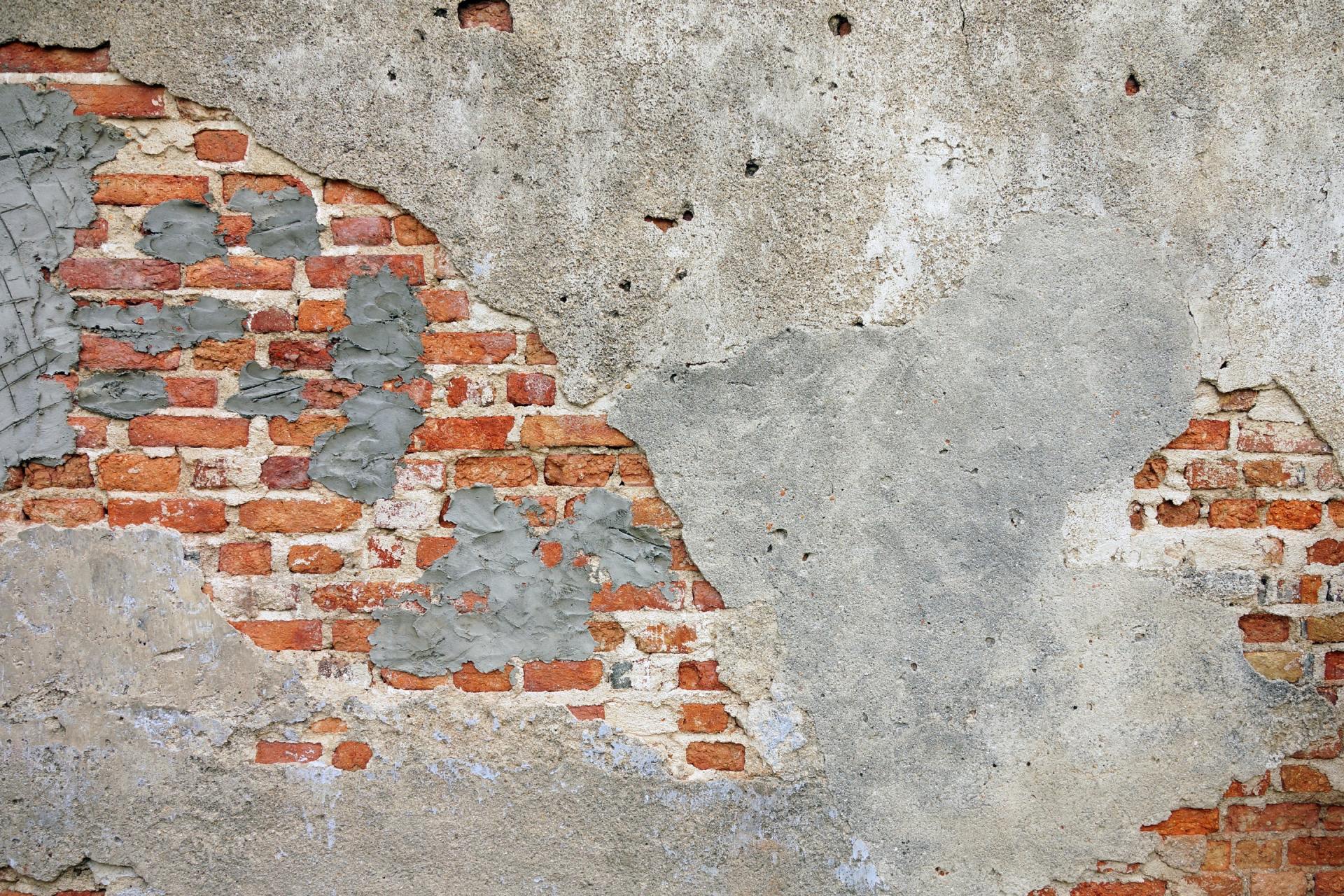 Old brick wall with peeling concrete in need of foundation repair