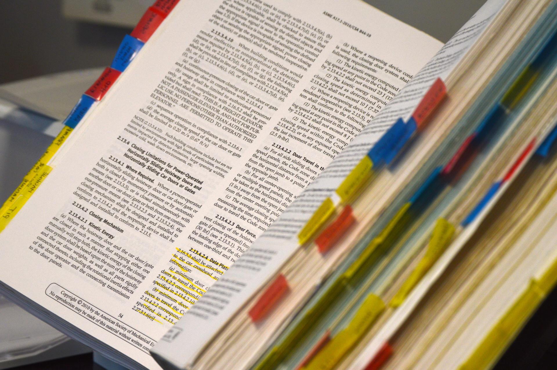 Open boek met kleurgecodeerde tabbladen en gemarkeerde tekst op de pagina's.