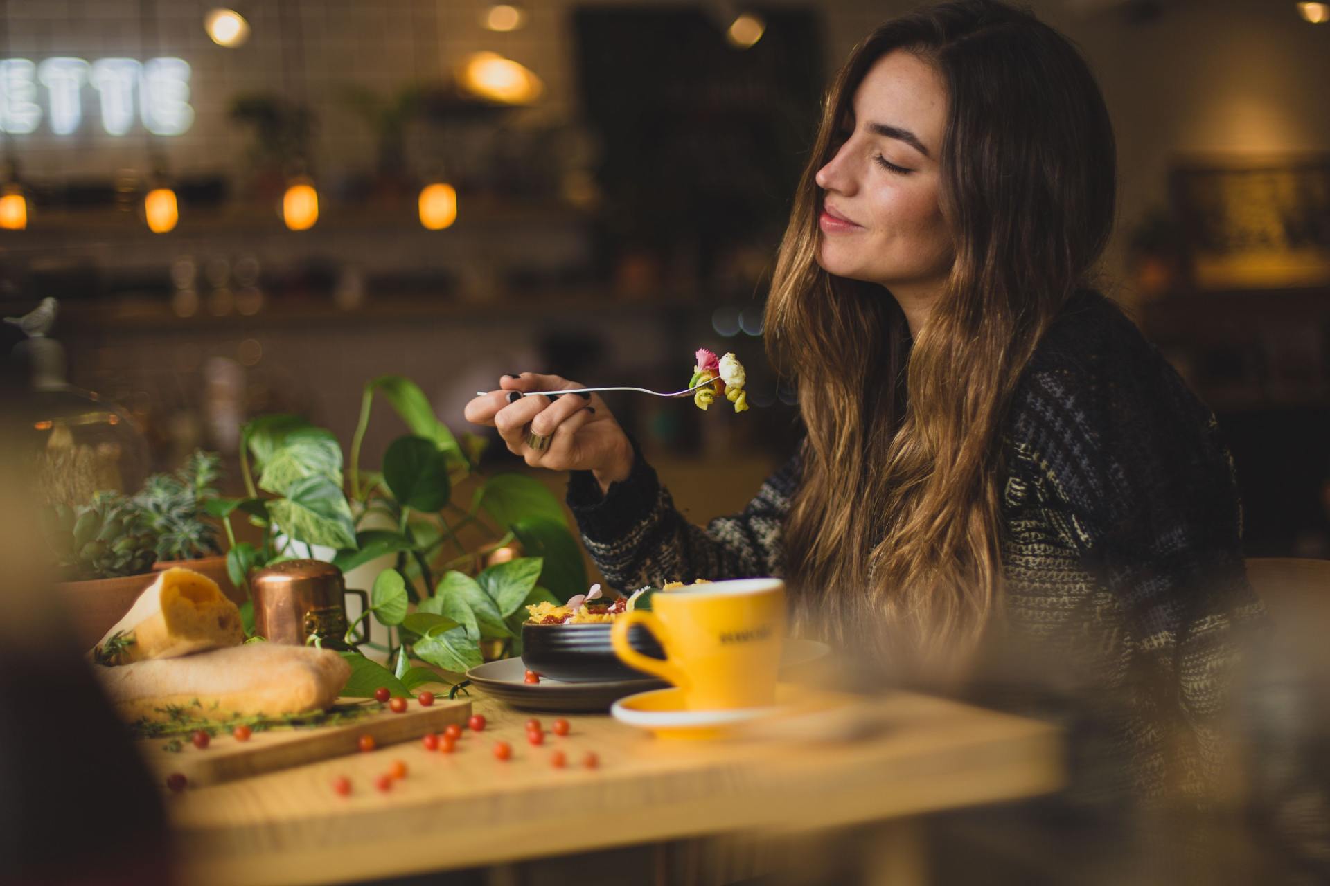 A woman is sitting at a table in a restaurant eating food.