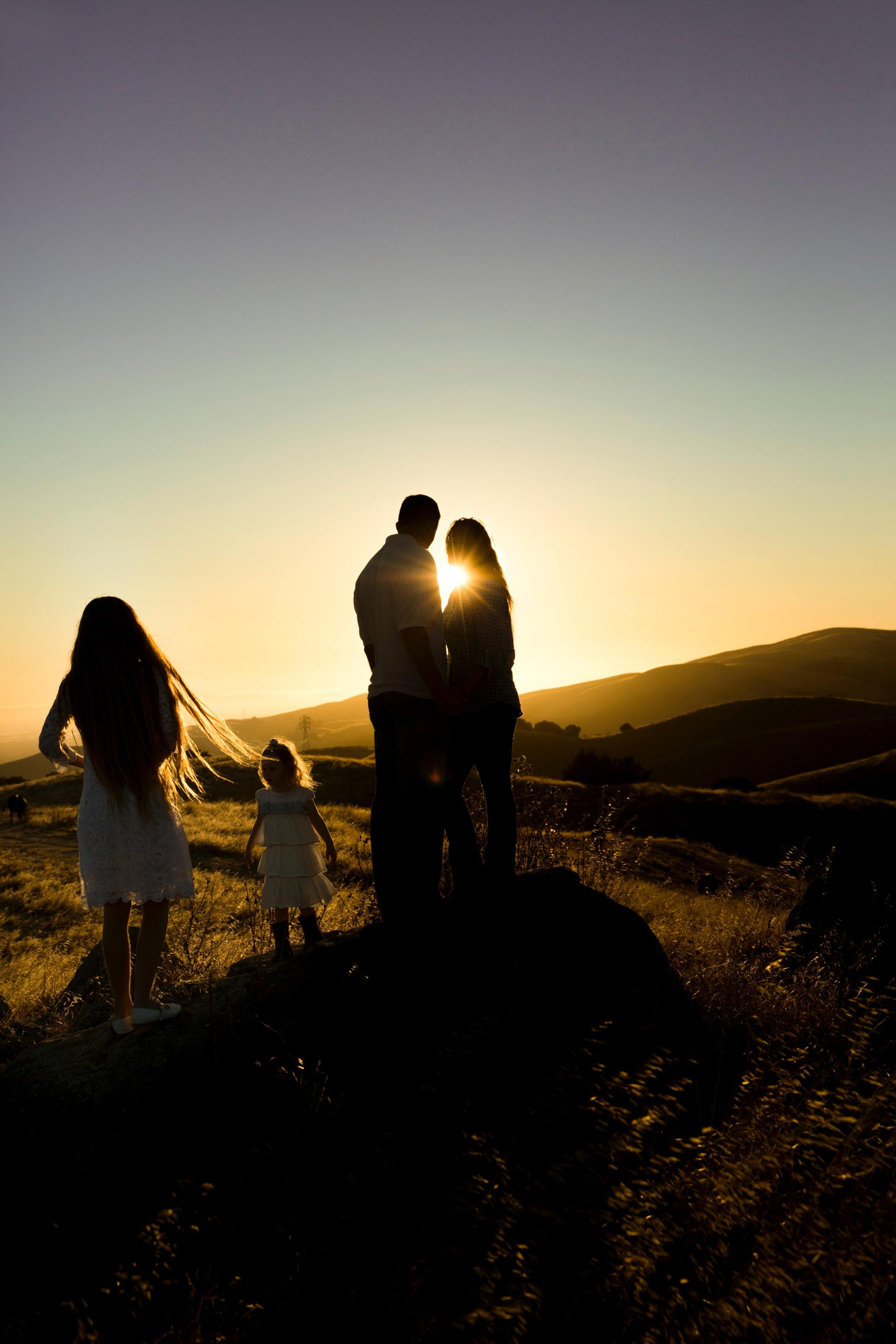 Una famiglia in piedi sulla cima di una collina al tramonto