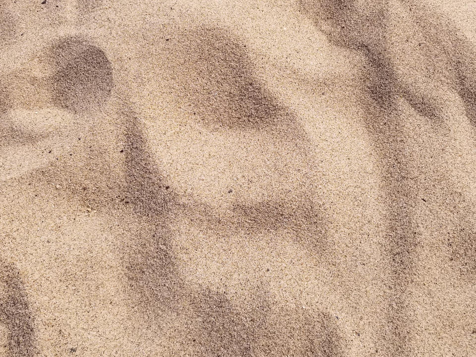 Soft beige fabric or sand with blurry dark shadows and texture.
