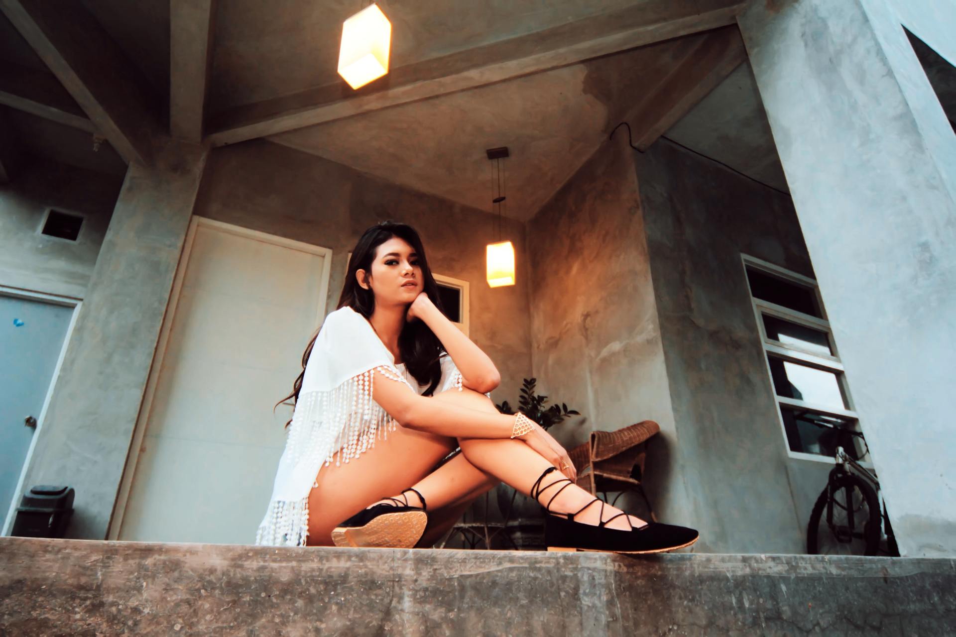 A woman is sitting on the steps of a building with her legs crossed.