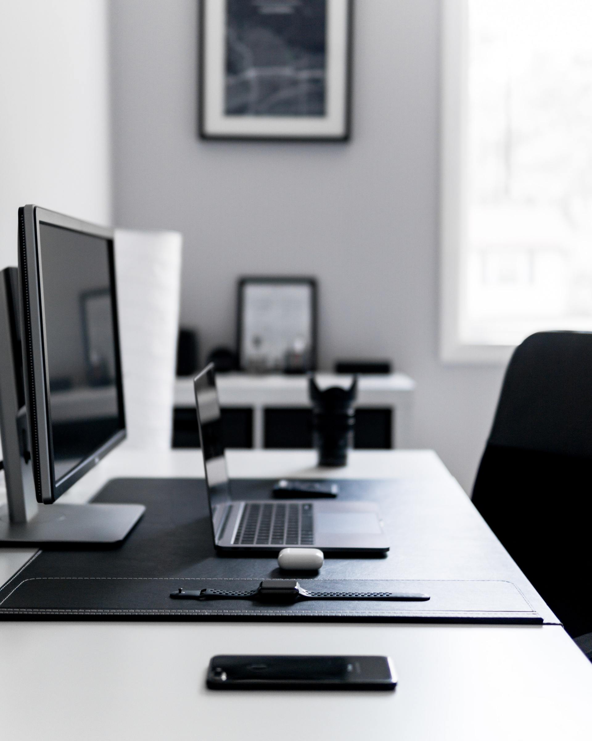 home office with desktop computer and open laptop nearby and black office chair