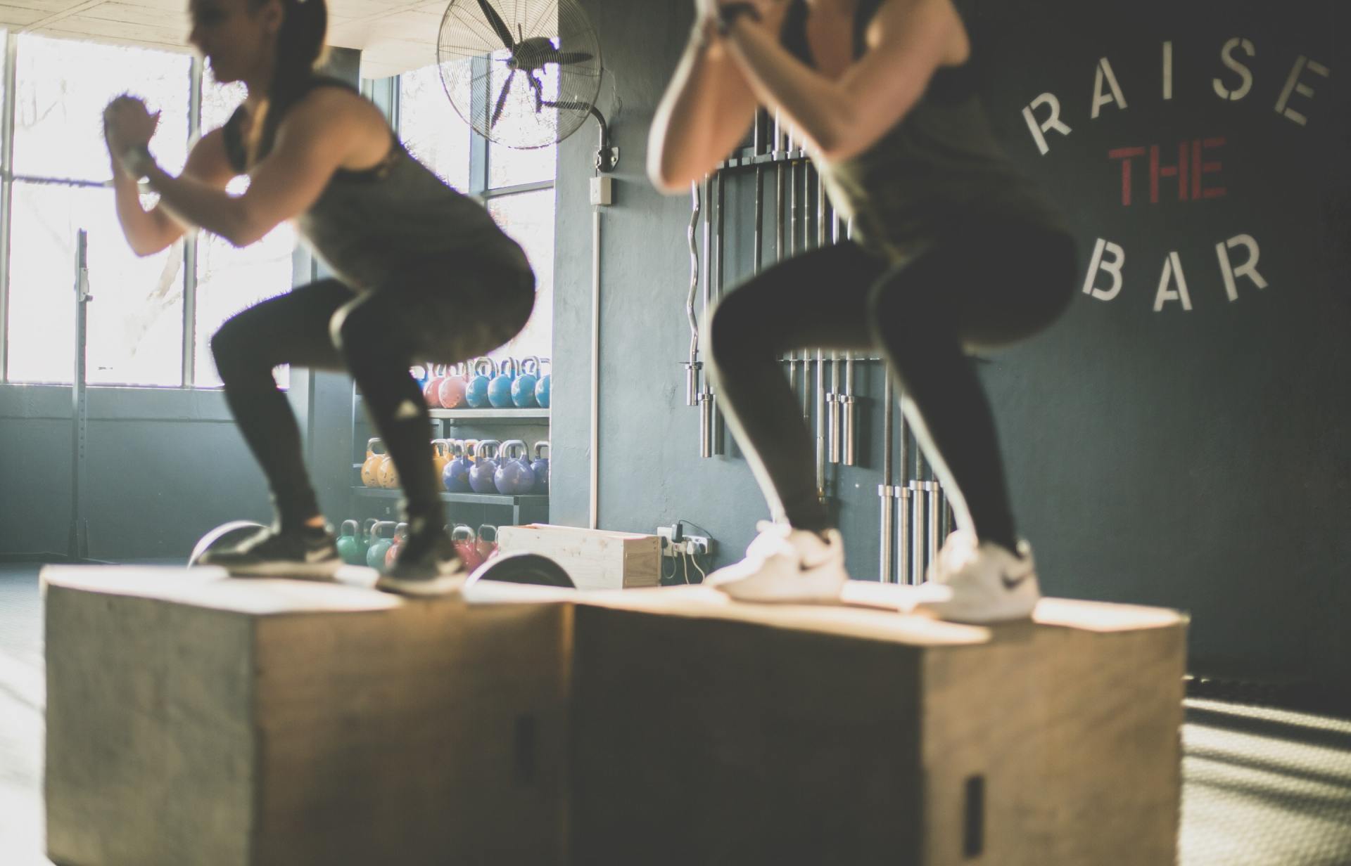 twee vrouwen hurken op dozen in een sportschool.