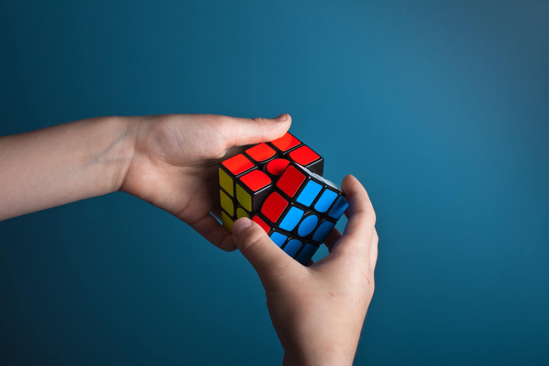 A person is holding a colorful rubik 's cube in their hands.