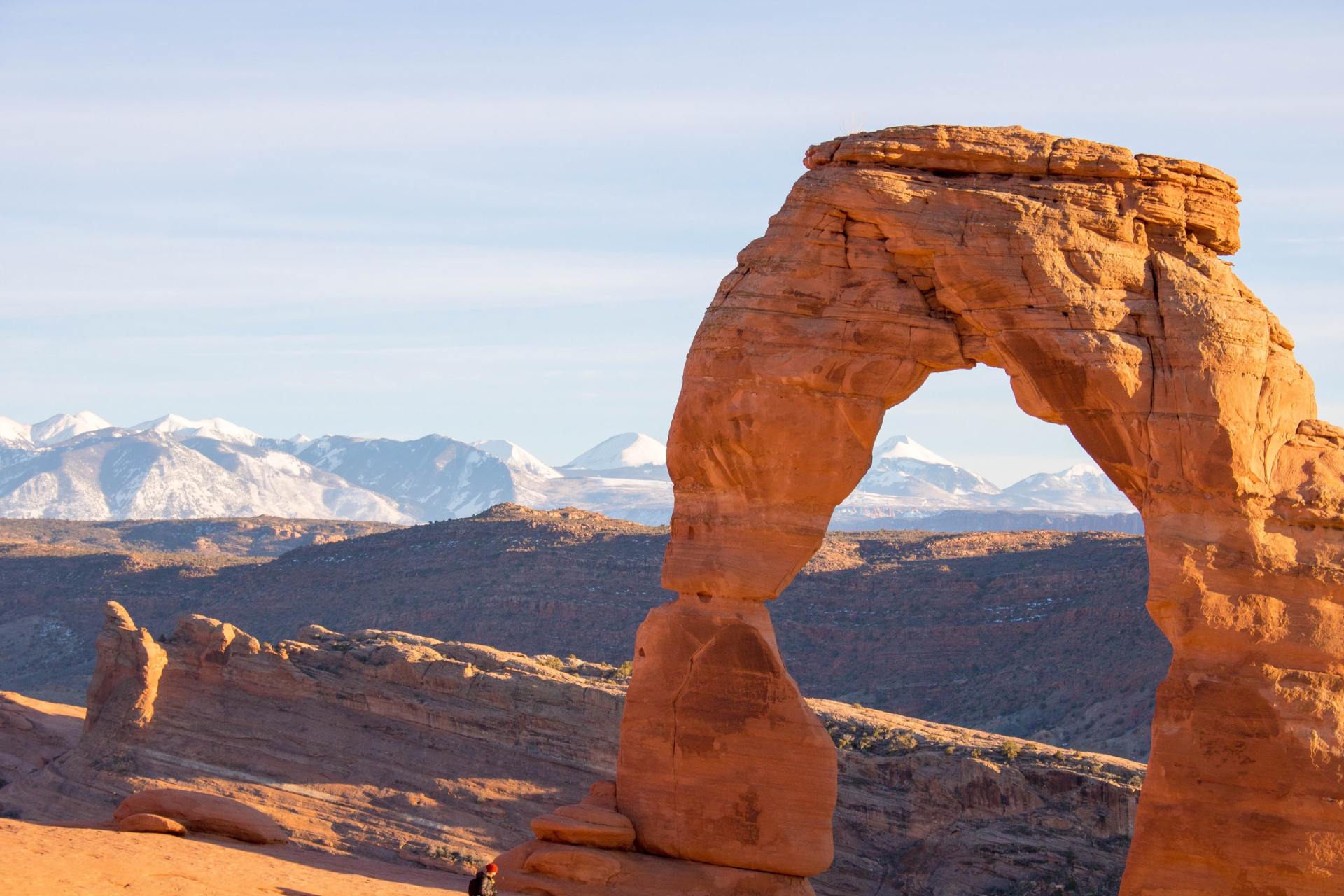 Delicate Arch in Arches National Park, Utah, with snow-capped mountains in the background.