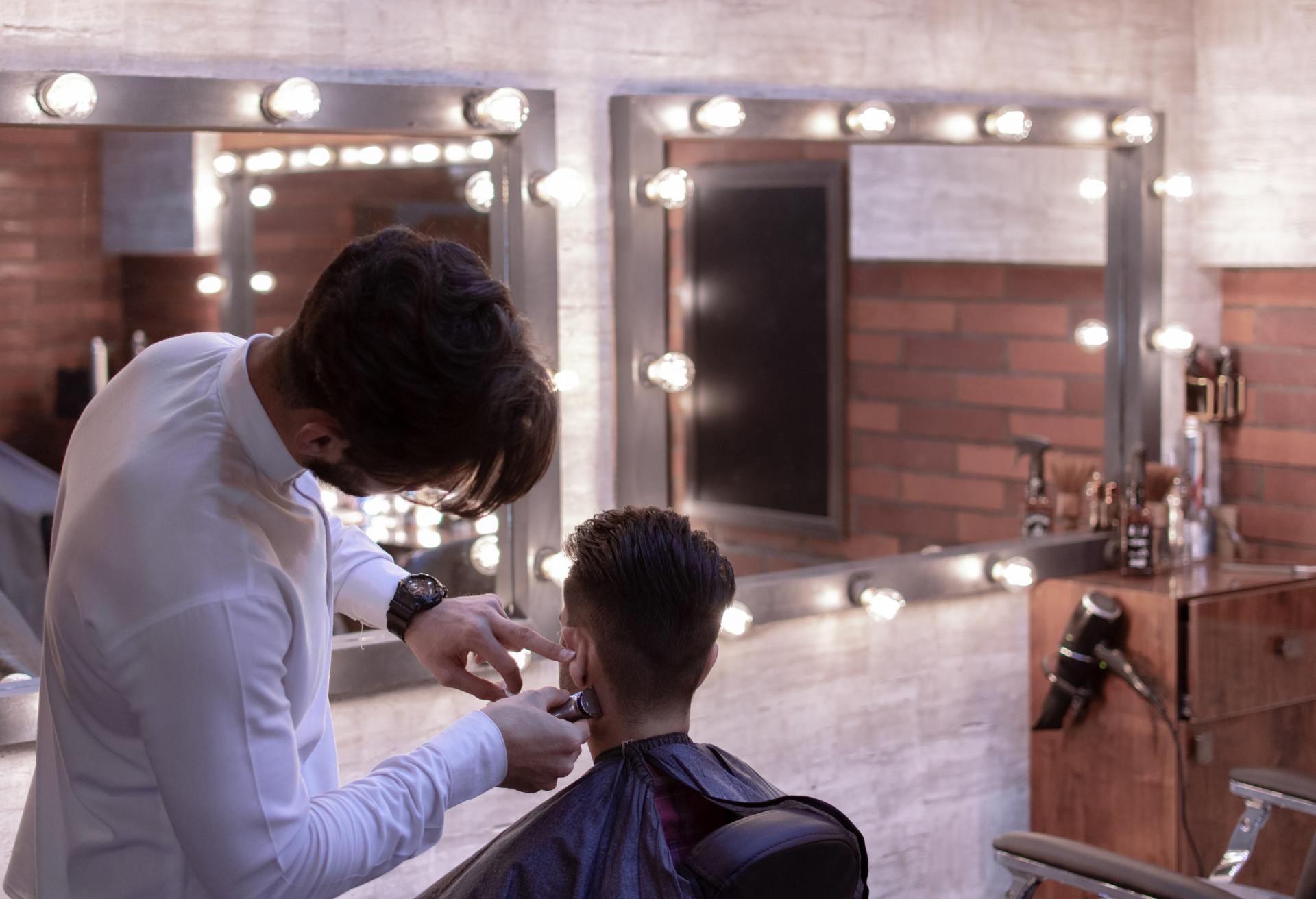 A man is getting his hair cut by a barber in a barber shop.