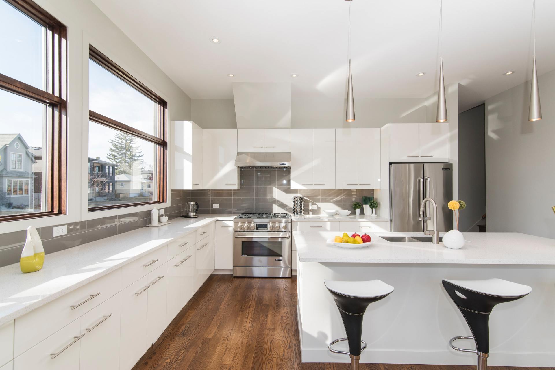 A kitchen with white cabinets , stainless steel appliances , and a large island.