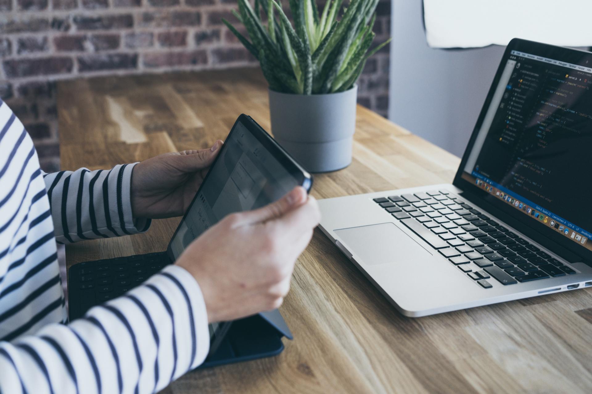 Criar o plano de aulas Uma pessoa está segurando um tablet na frente de um laptop.