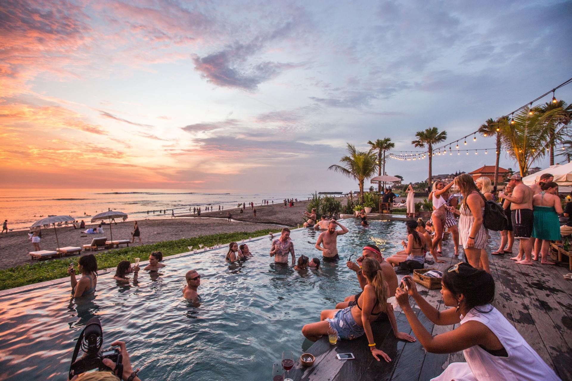 Eine Gruppe von Leuten steht um einen Swimmingpool an einem Strand herum.