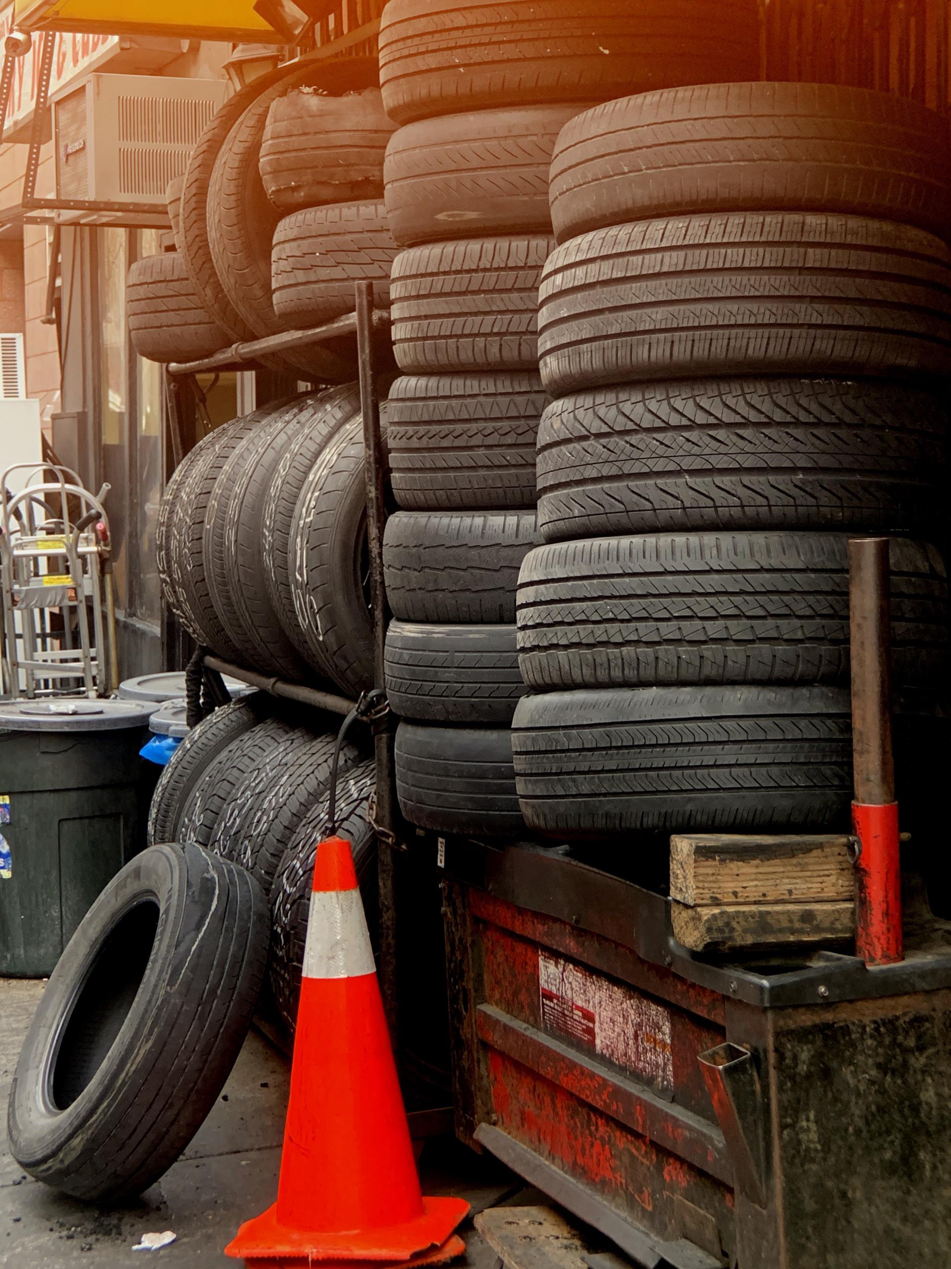 A bunch of tires are stacked on top of each other in a garage.