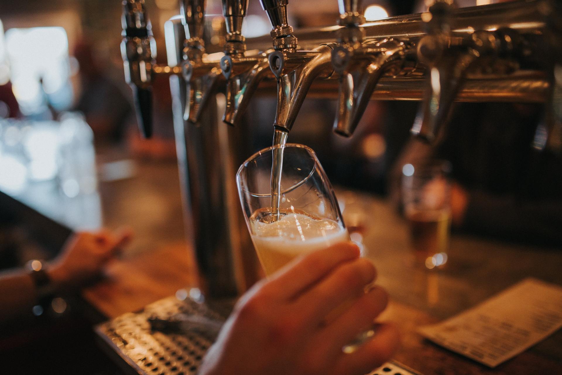 A person is pouring beer into a glass at a bar.