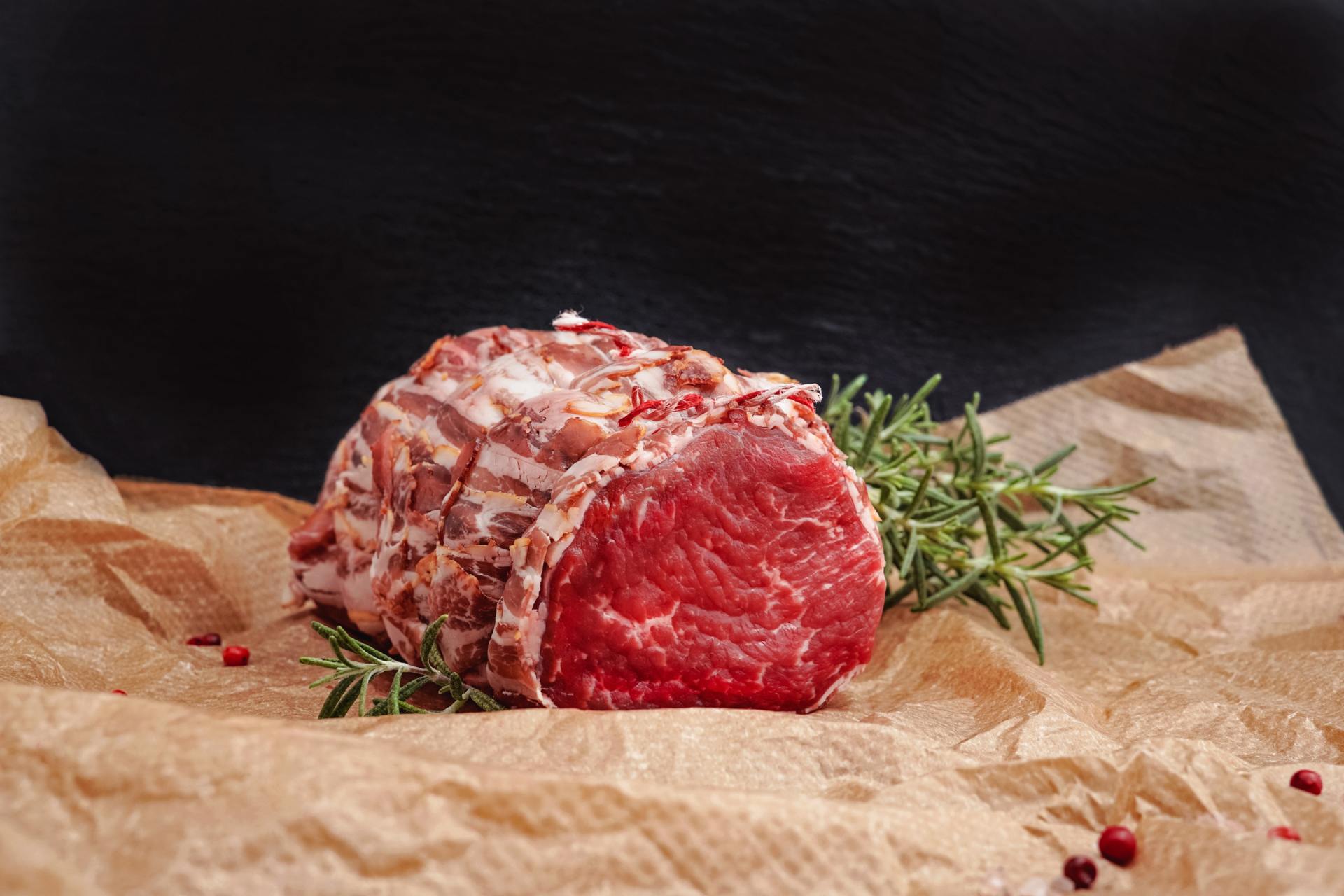 A piece of raw beef is sitting on a piece of brown paper.