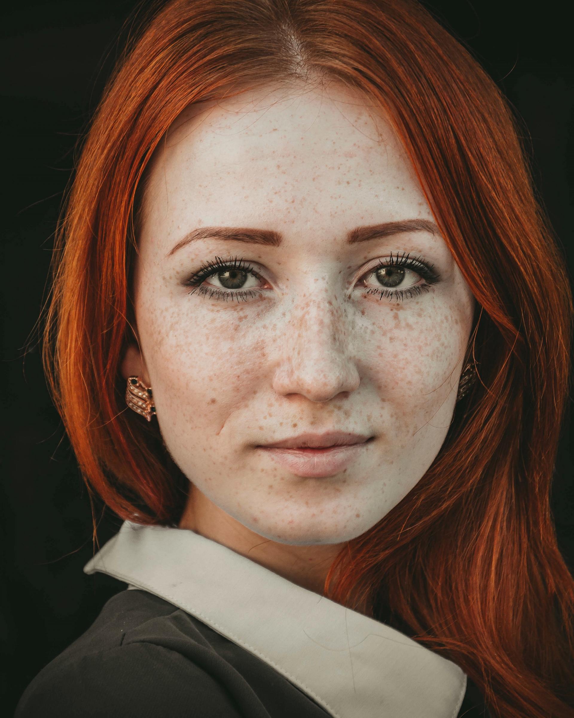 A close up of a woman 's face with red hair and freckles.