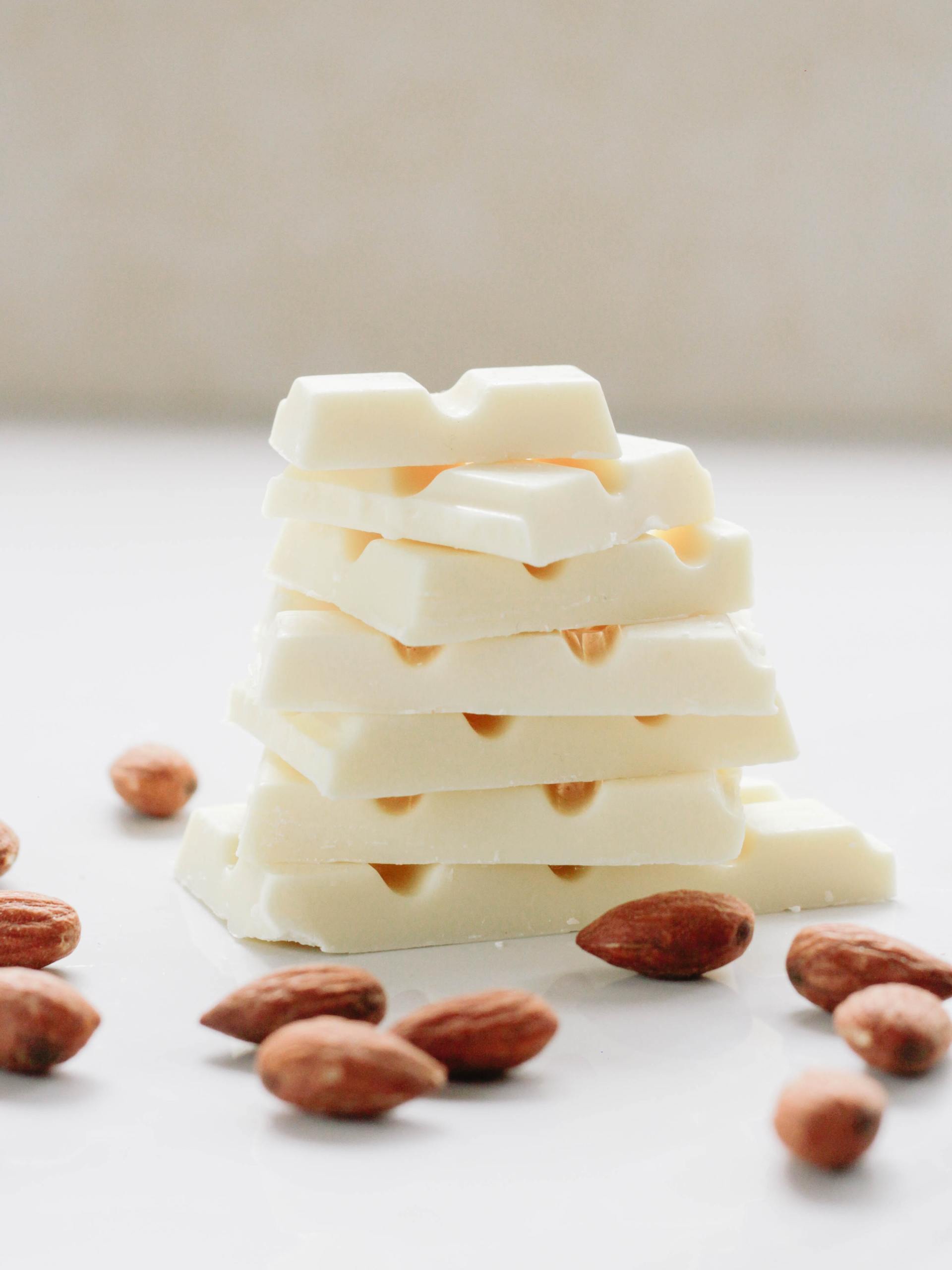 White chocolate bar pieces stacked with almonds scattered around.