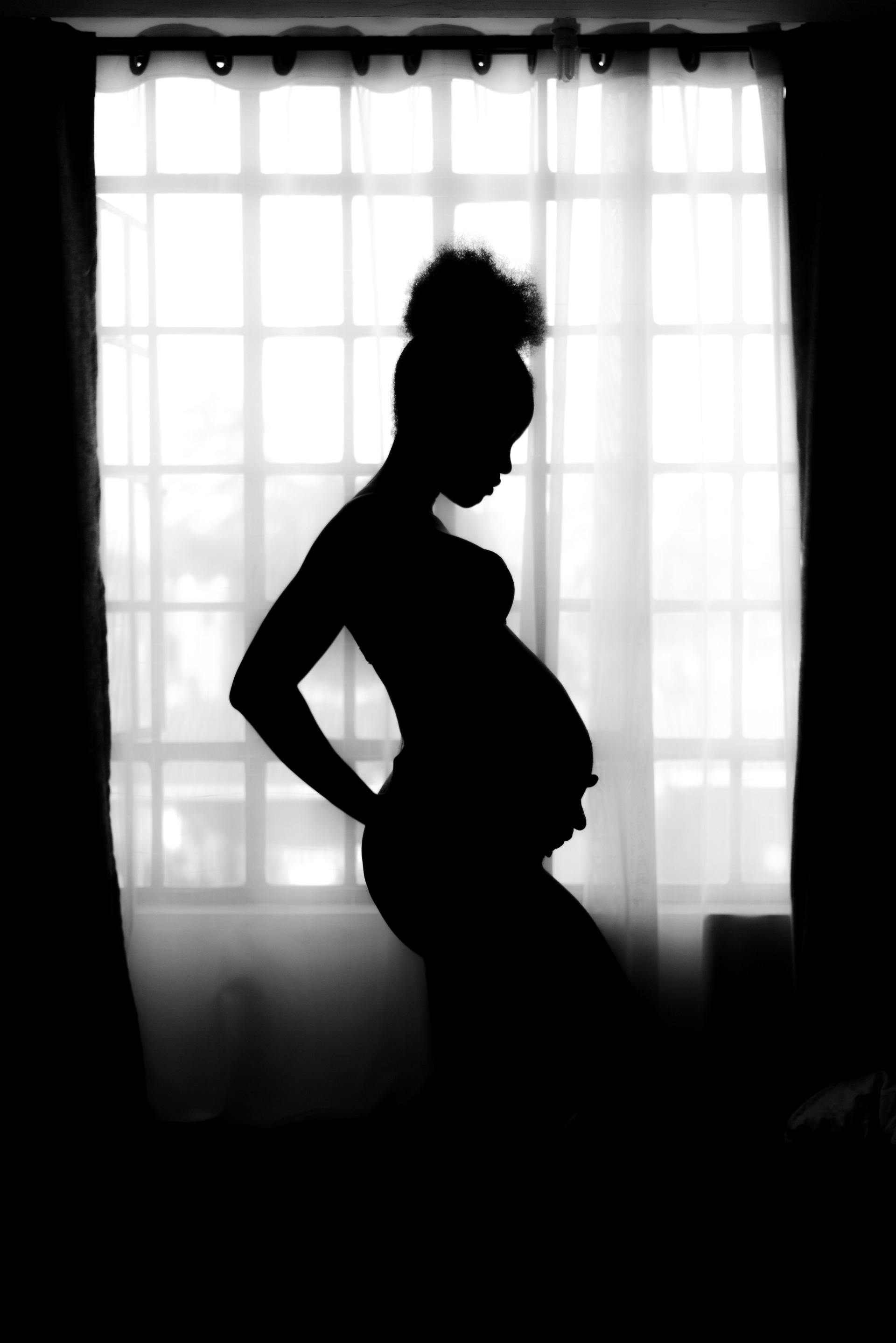 Pregnant woman in silhouette against window