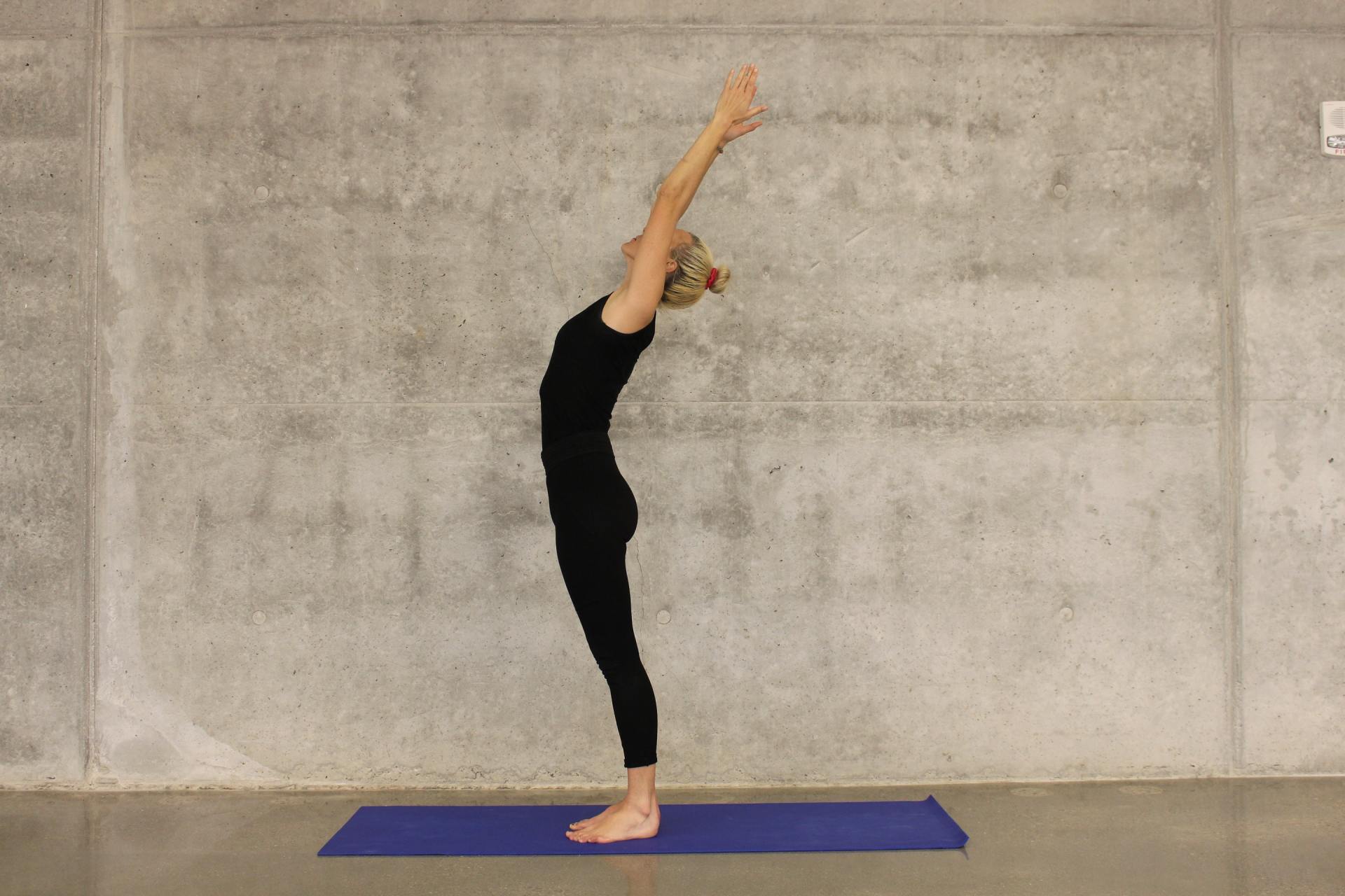 Eine Frau macht eine Yoga-Pose auf einer blauen Matte.