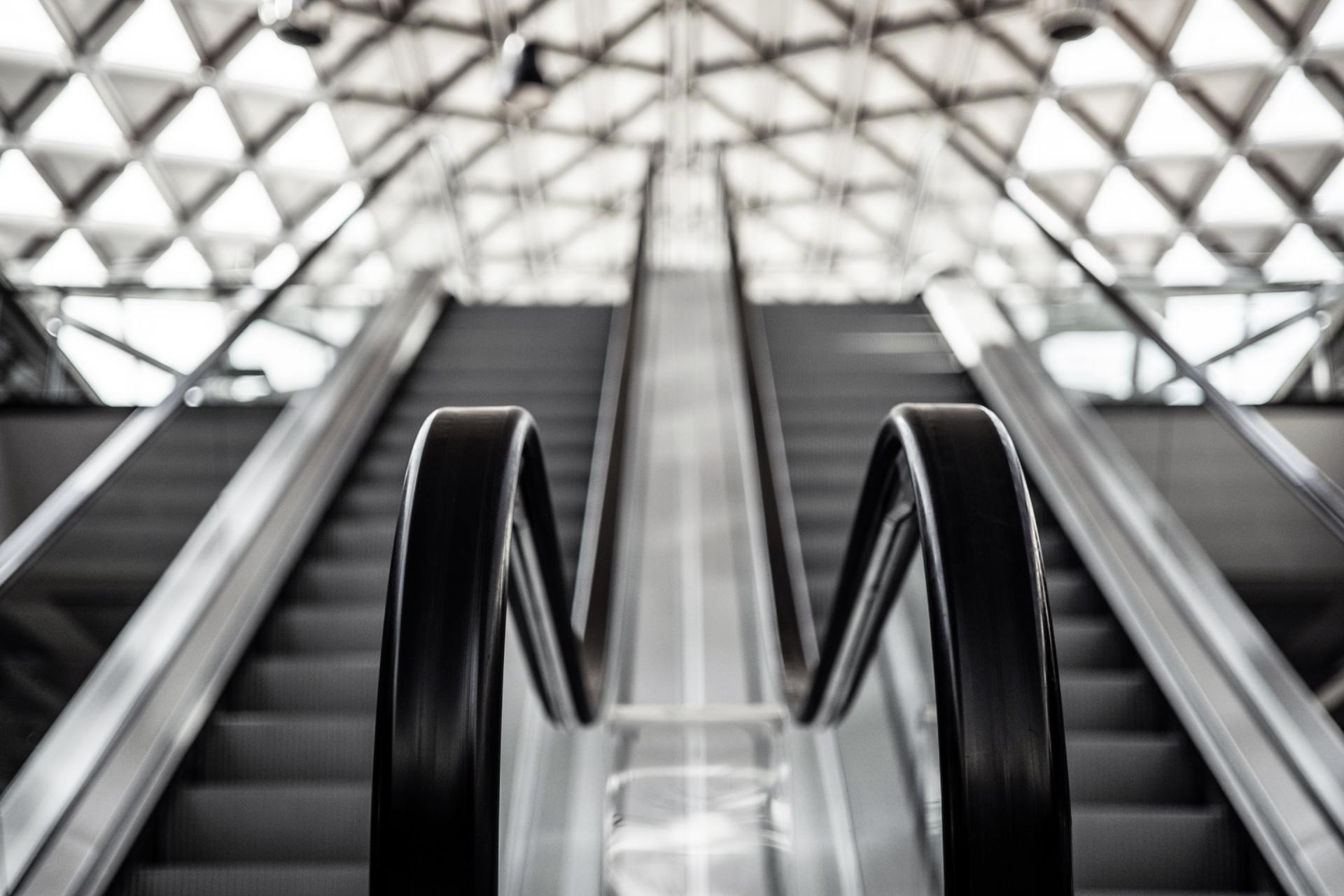 A black and white photo of an escalator in a building.