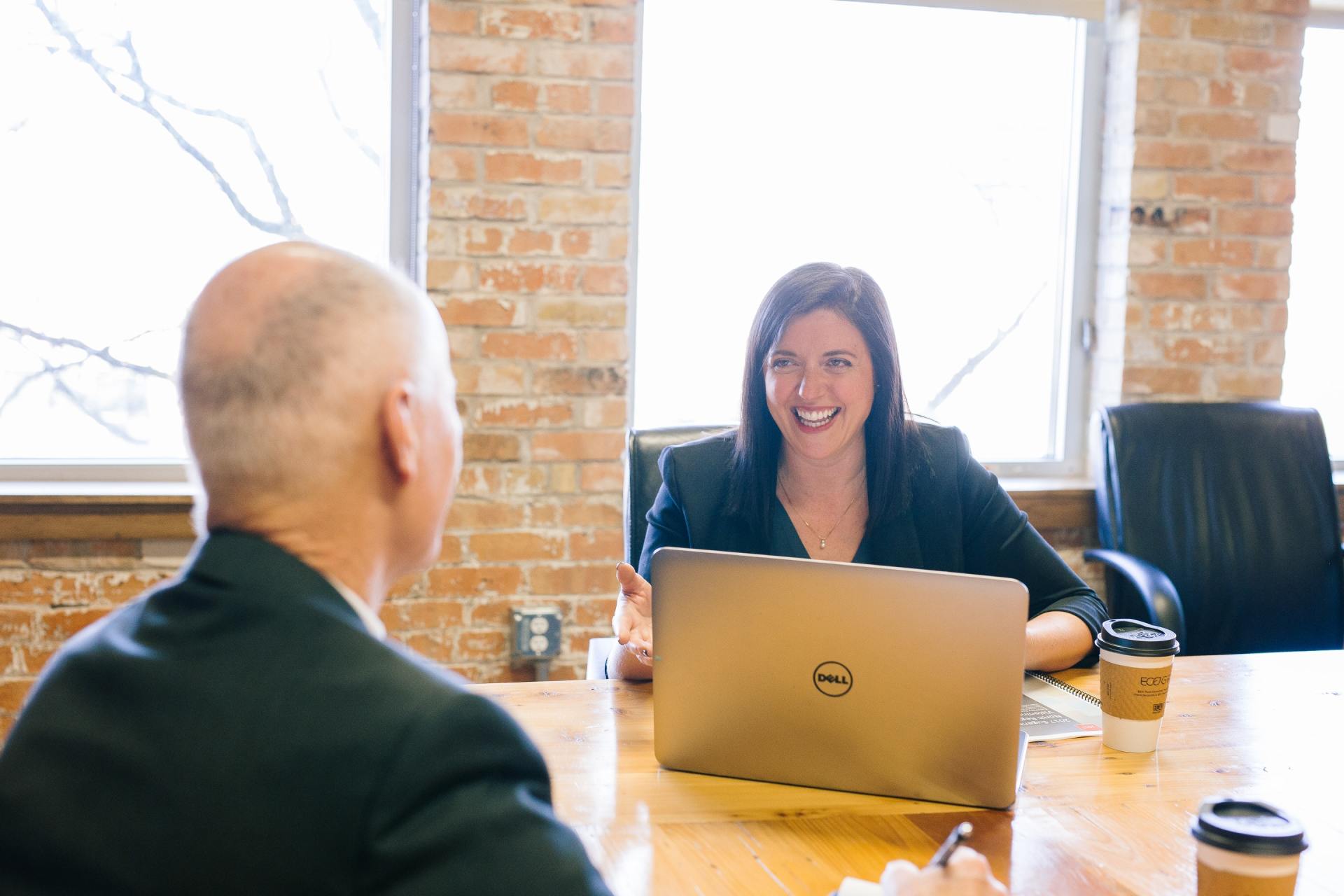 A man and a woman are sitting at a table with a laptop