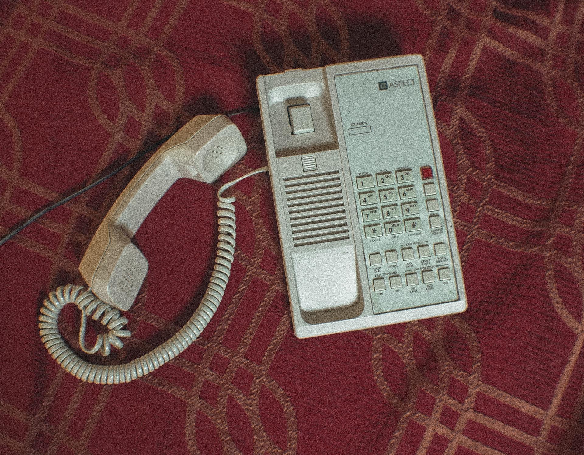 A white telephone is laying on a red carpet