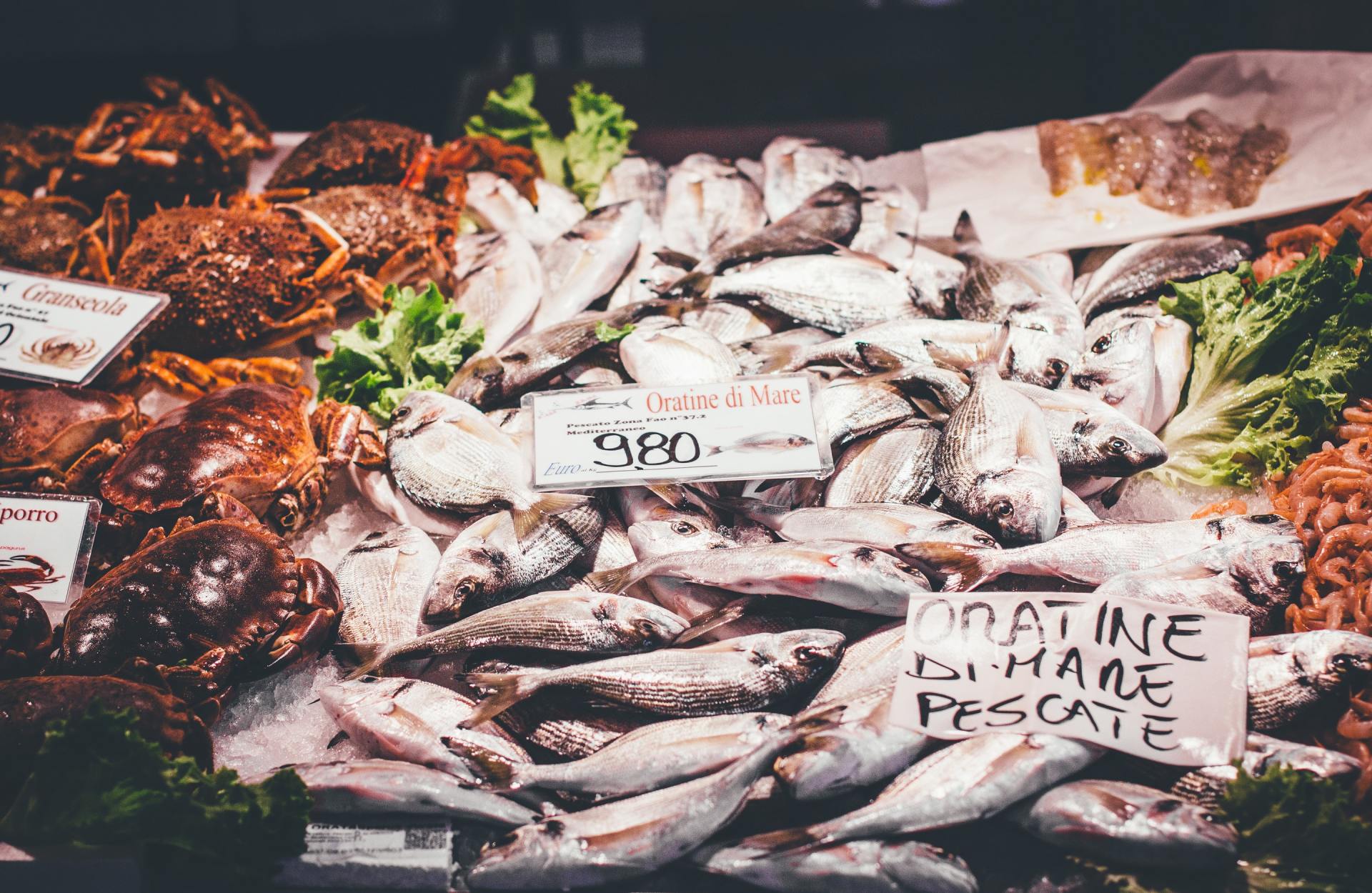 En un mercado de pescado se exhibe una variedad de pescados y cangrejos sobre hielo.