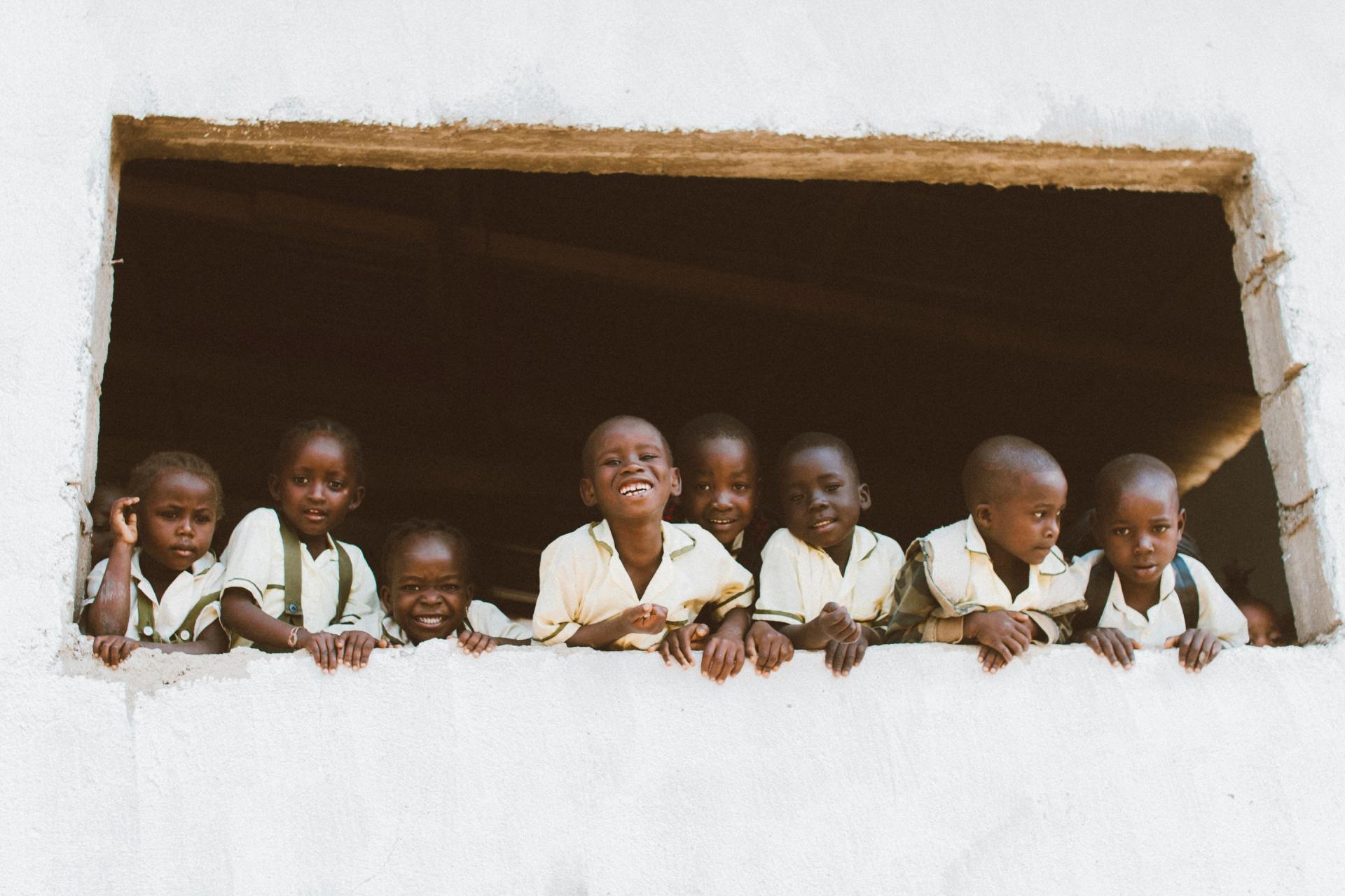 A group of children are looking out of a window.
