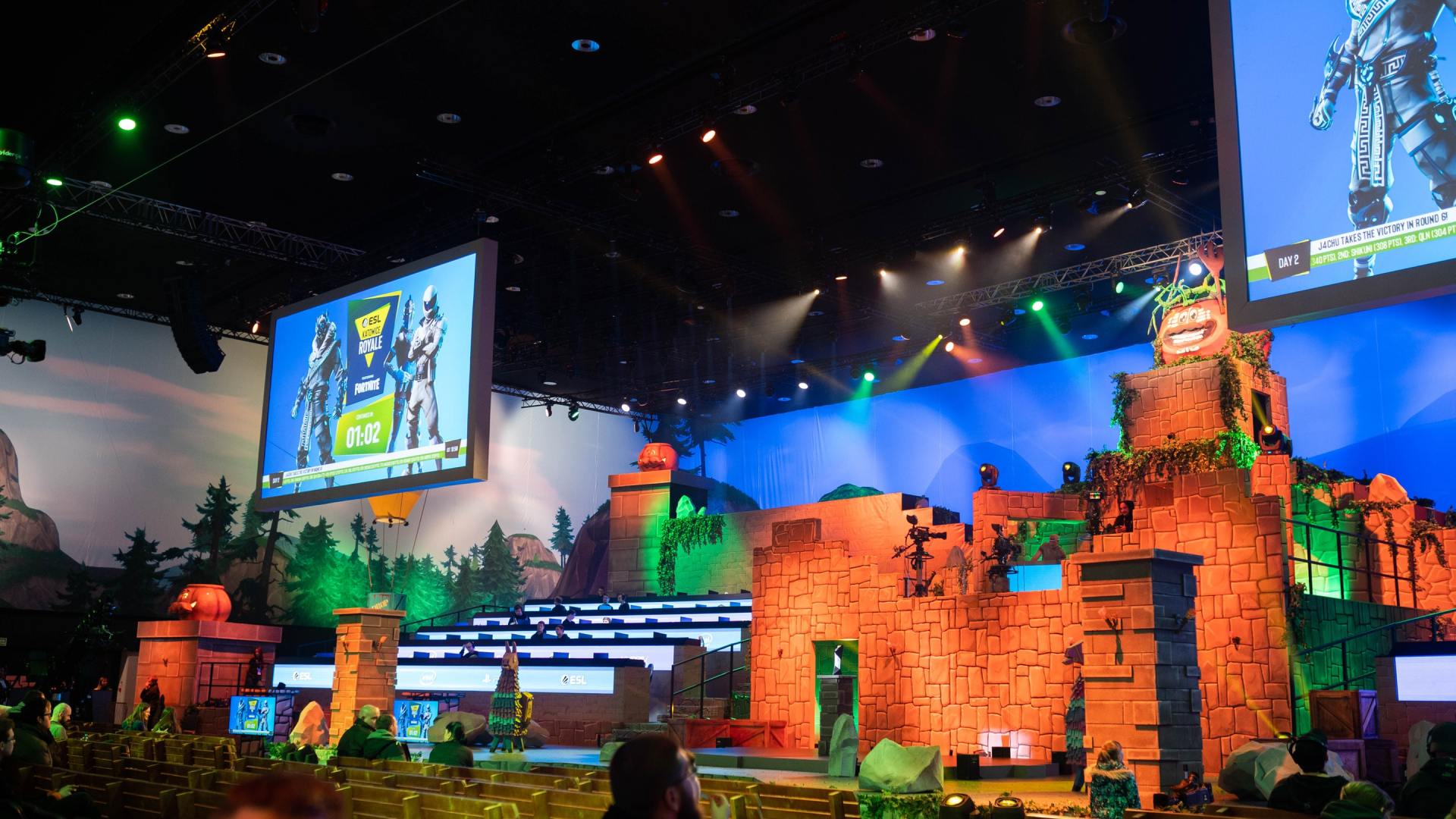 Stage set with castle props and large screens under colorful lights at an indoor event
