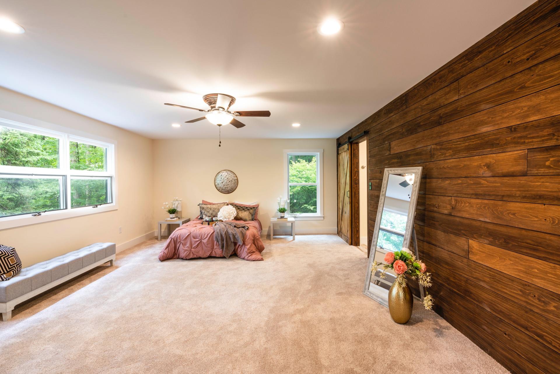 A bedroom with a bed , ceiling fan , and wooden wall.
