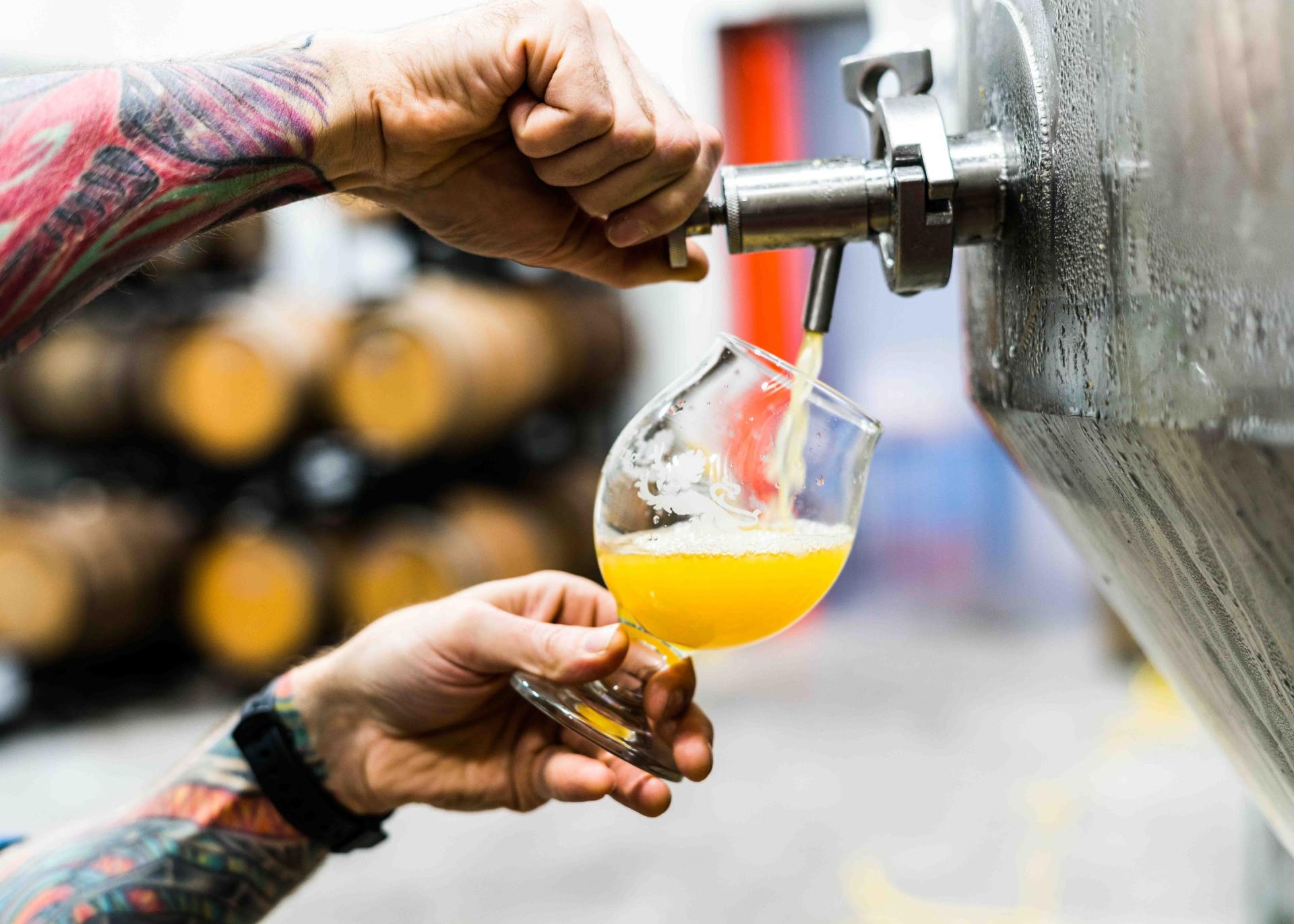 a person is pouring beer into a glass from a tap .