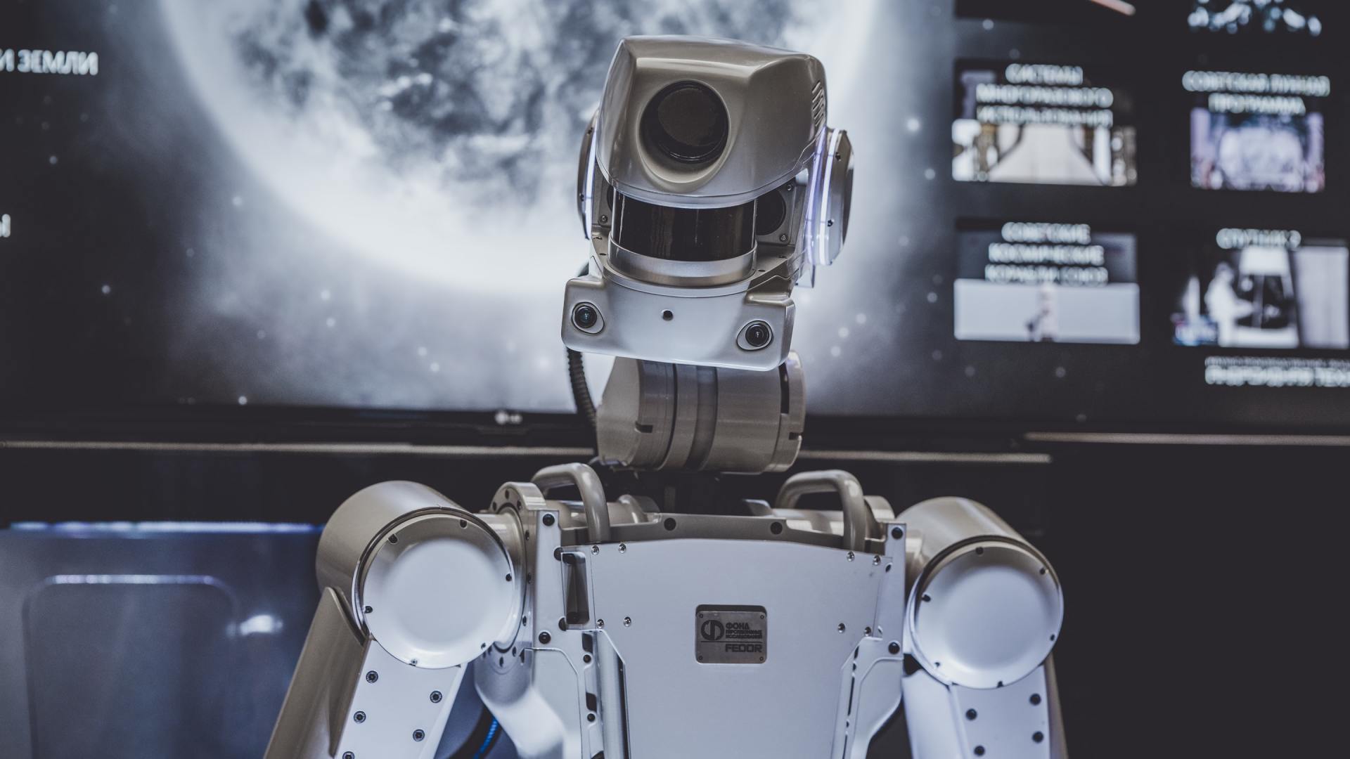 A robot is standing in front of a computer screen.