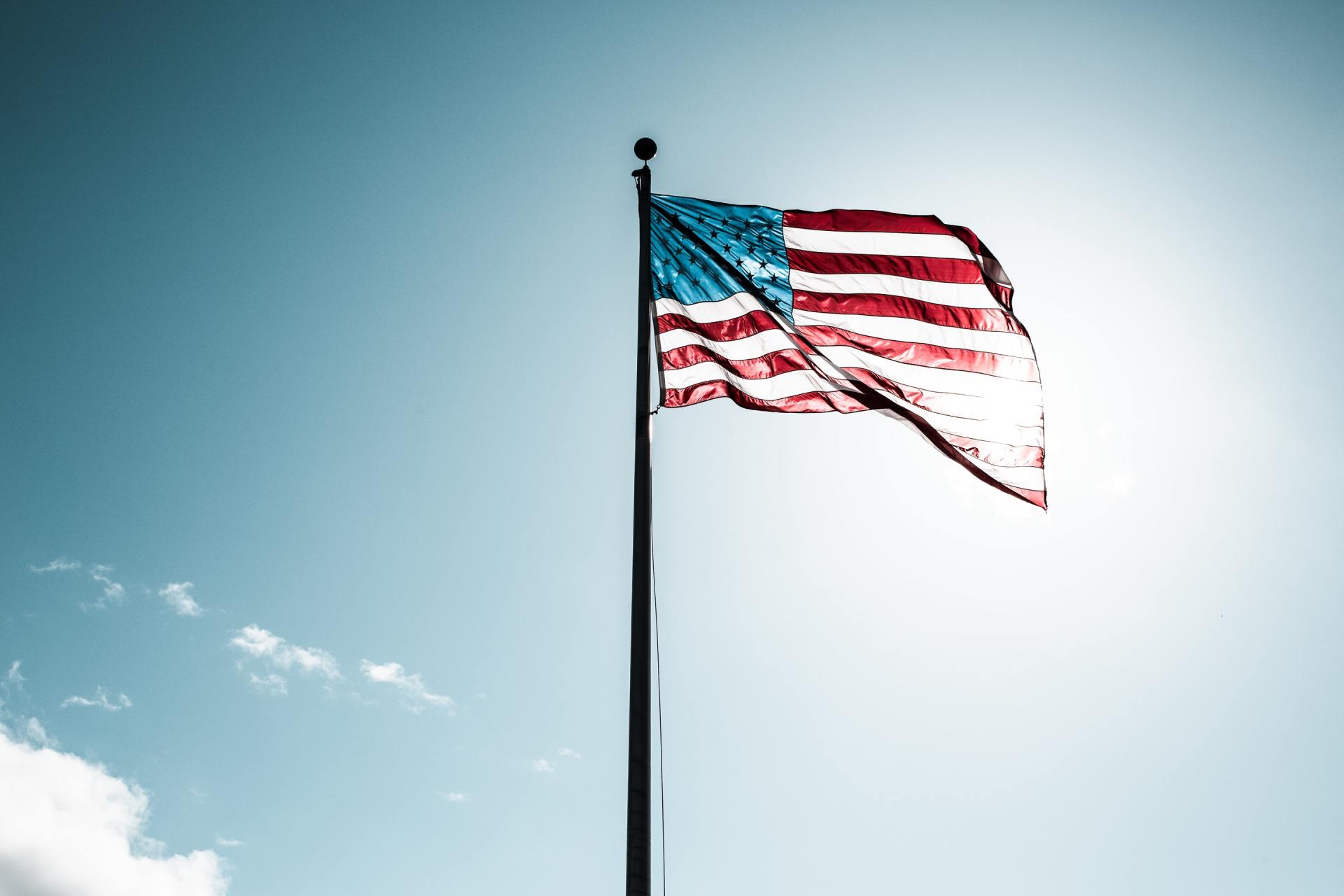American flag waving against a bright blue sky.