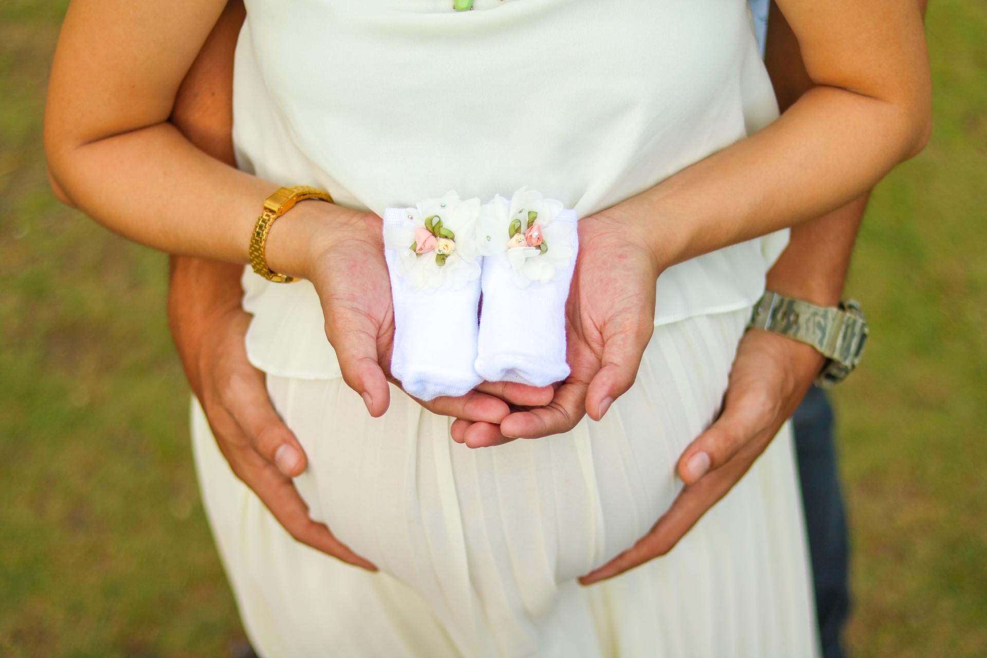 mother holding unborn child's cloth father holding mother's tummy