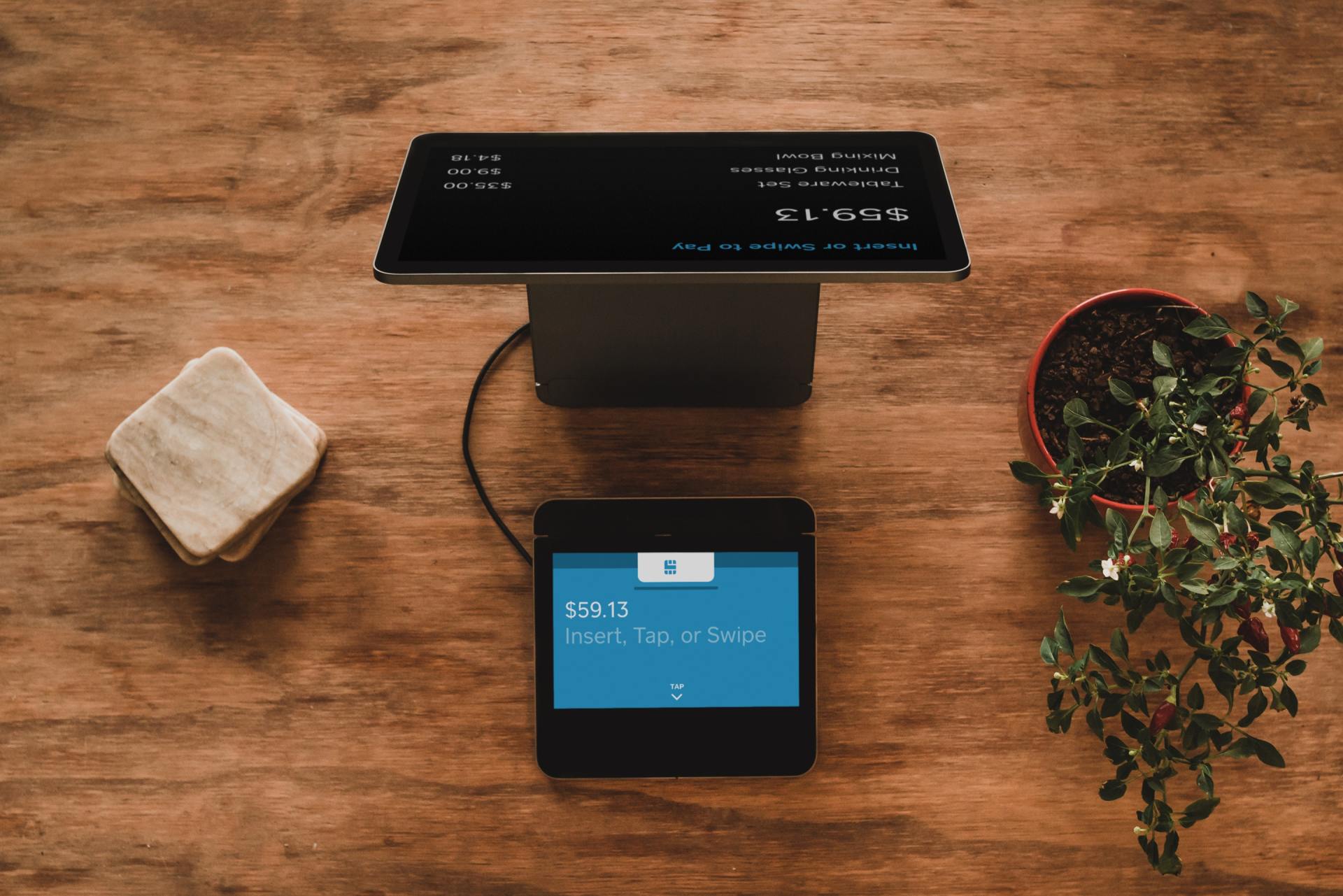 A tablet is sitting on top of a wooden table next to a potted plant.