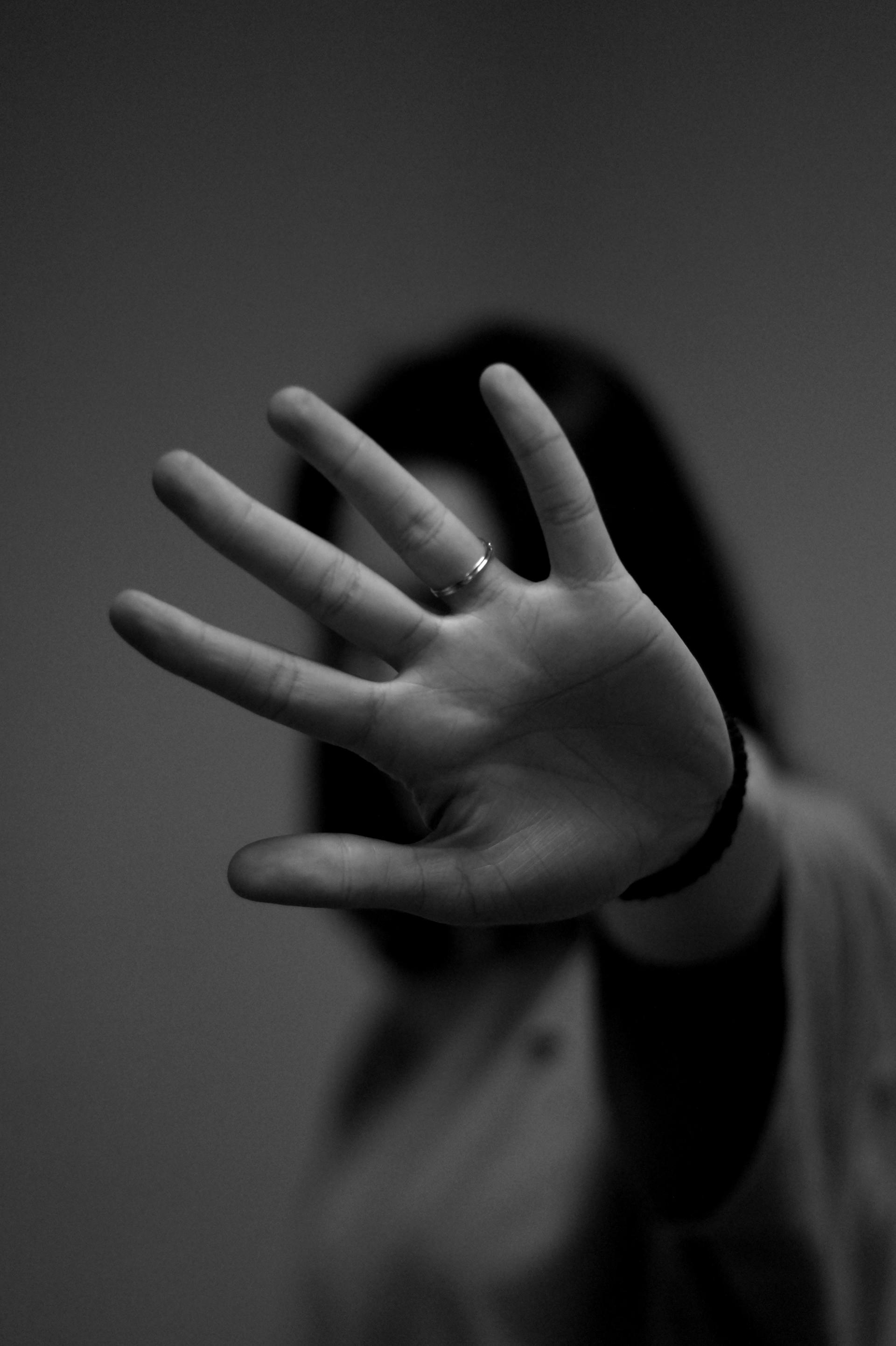 A woman is covering her face with her hand in a black and white photo.
