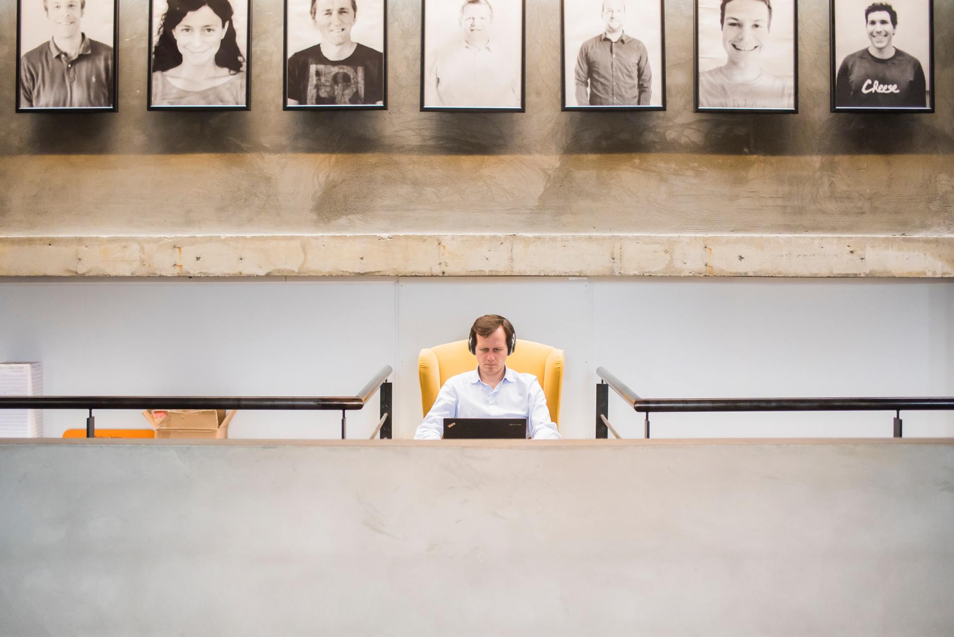 A man wearing headphones sits at a desk with a laptop