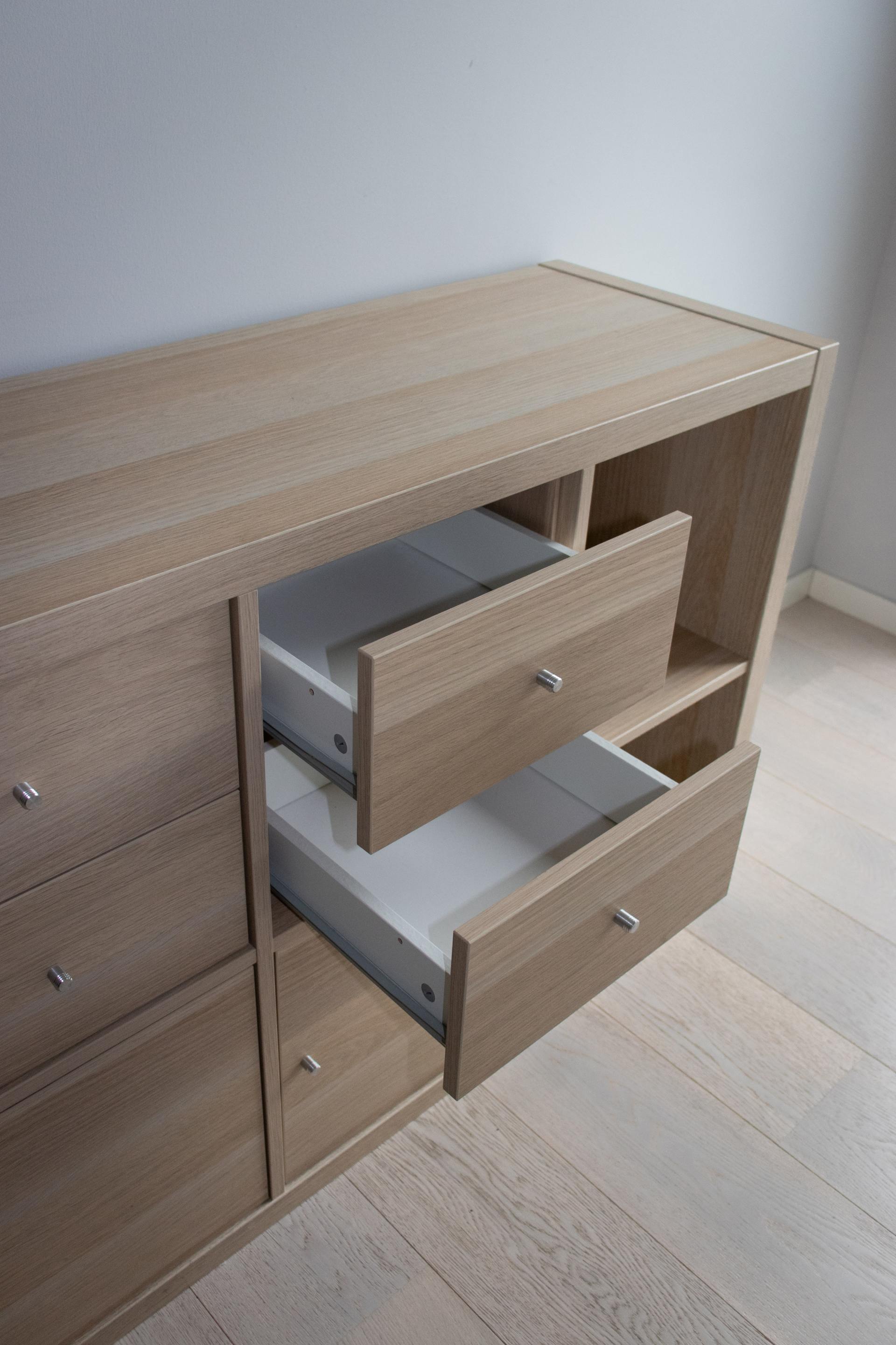 A wooden dresser with two drawers open in a room.
