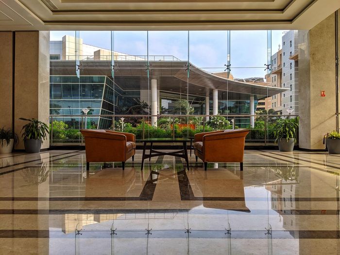 Two leather chairs face a table in front of a glass wall overlooking an outdoor patio.
