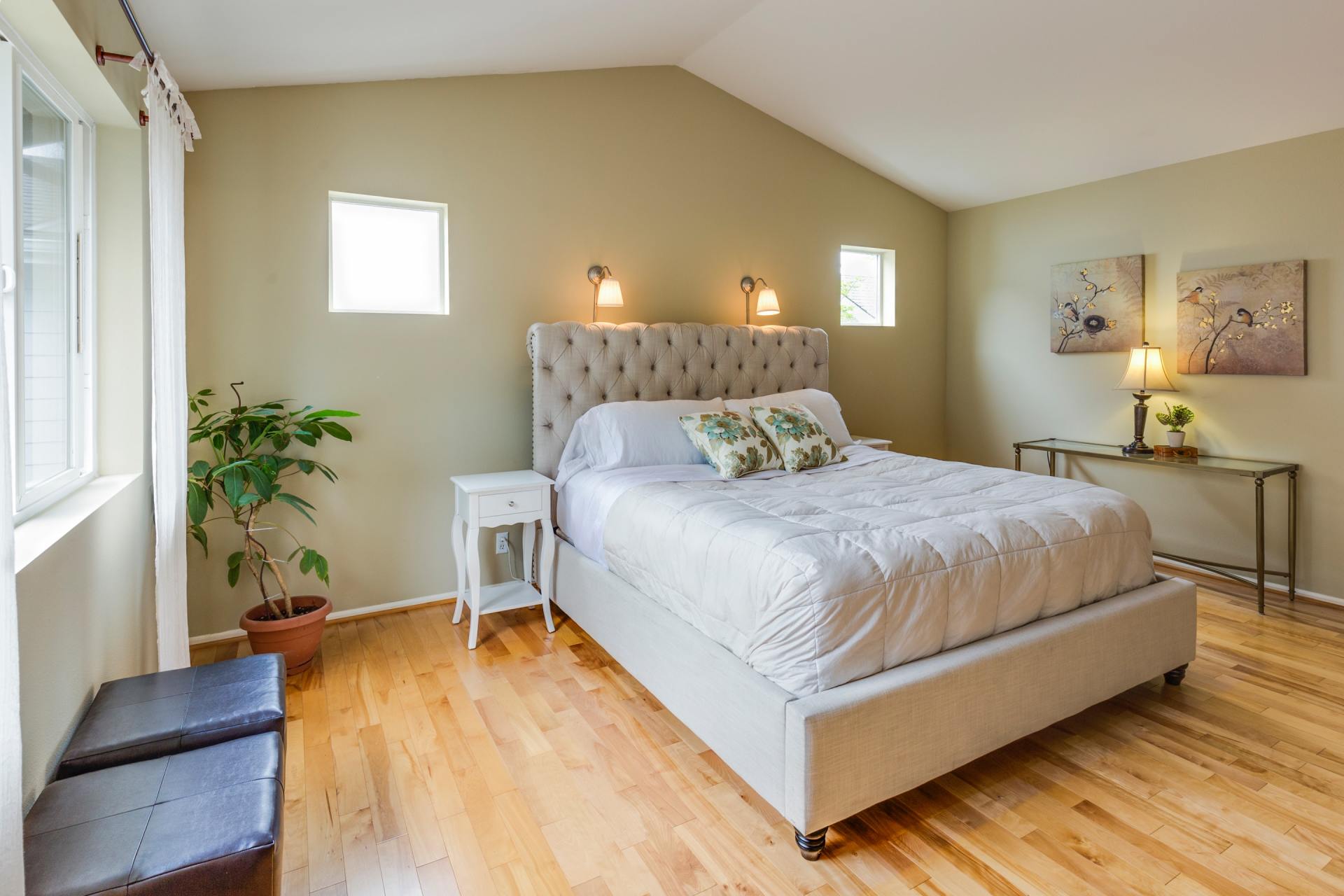 A bedroom with hardwood floors , a bed , two nightstands , and a window.
