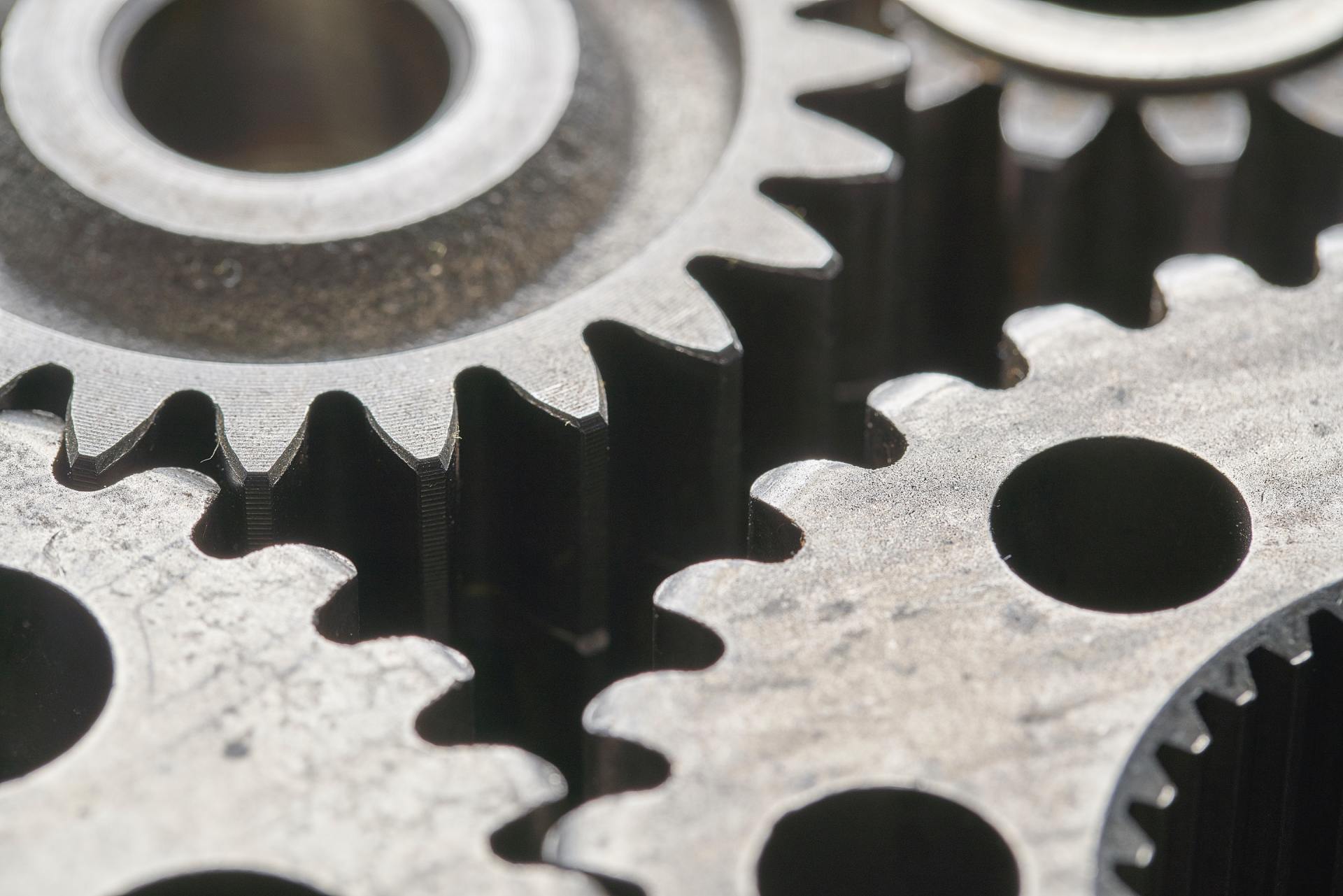 Close-up of interlocking metal gears with silver teeth and dark circular holes