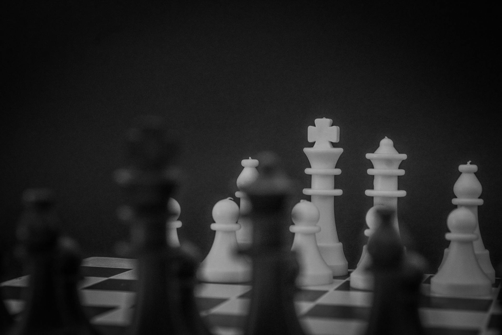 A black and white photo of a chess board with chess pieces on it.