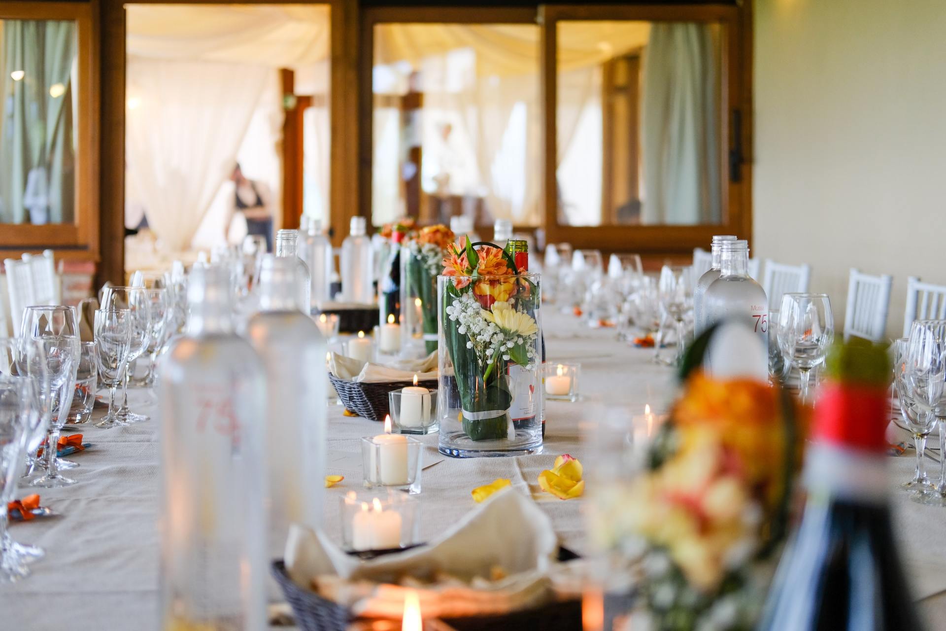 Long table set for a wedding, with flowers, candles, and glassware.