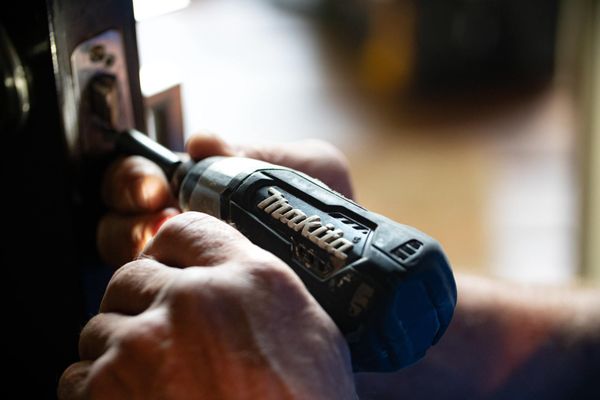 using a drill to screw in a door latch