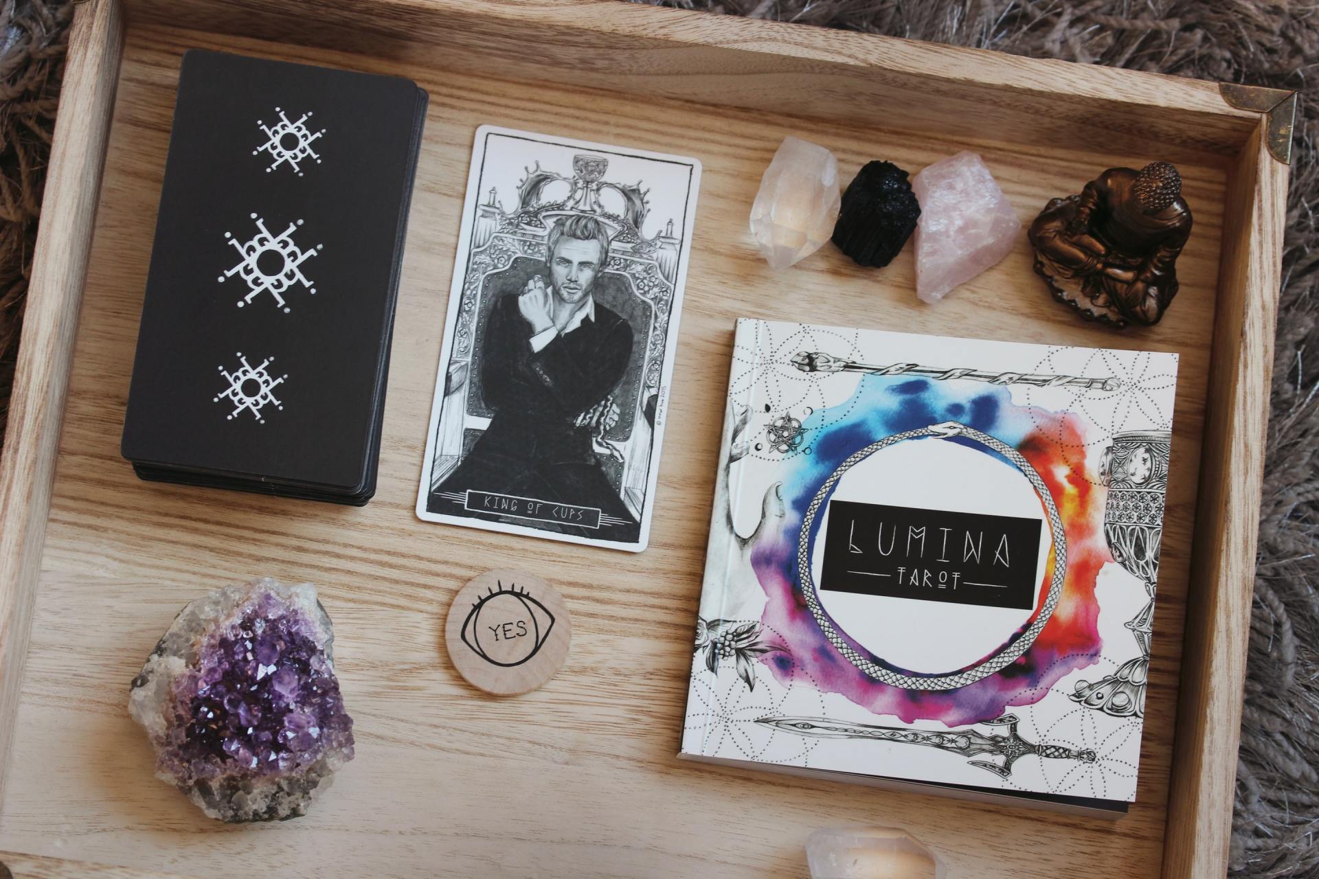A wooden tray with tarot cards and crystals on it