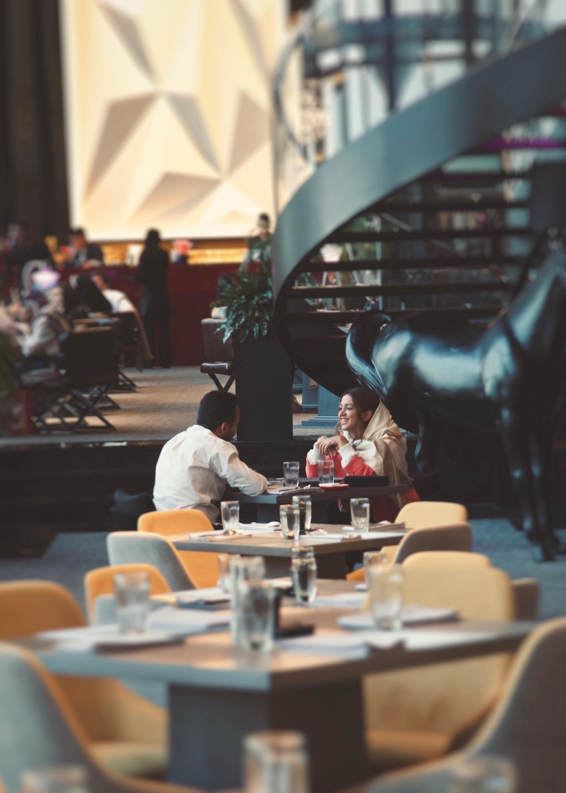 A man and a woman are sitting at tables in a restaurant.