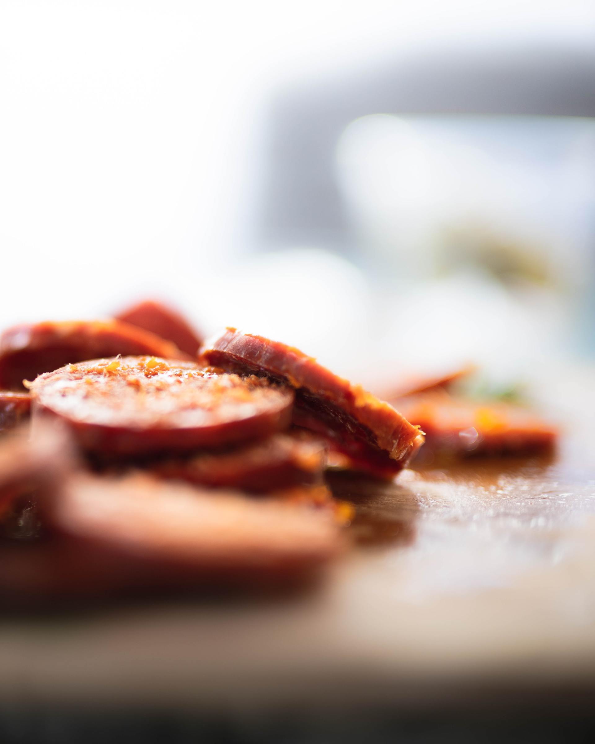 A close up of sliced pepperoni on a cutting board.