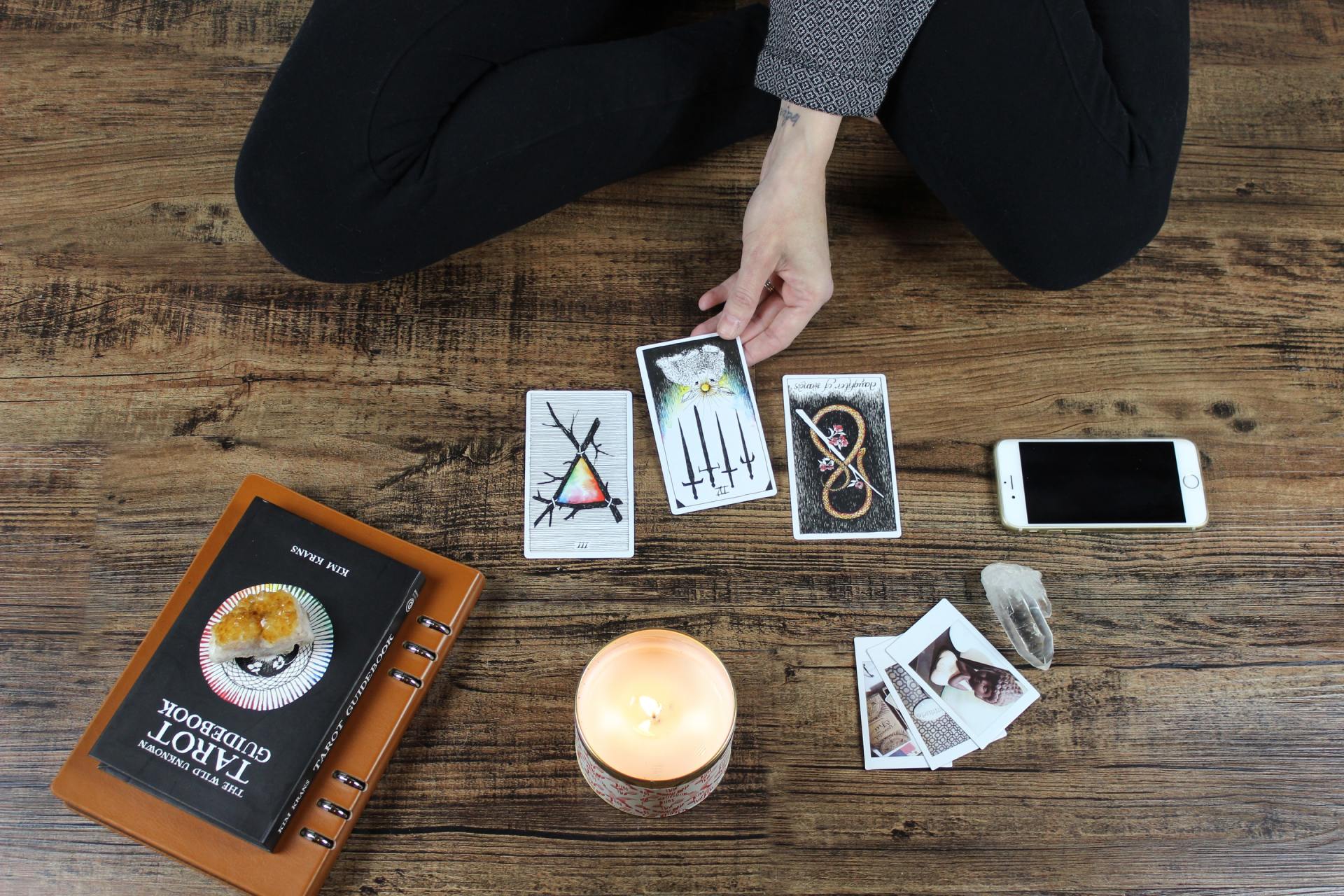 A woman is kneeling on the floor playing tarot cards.