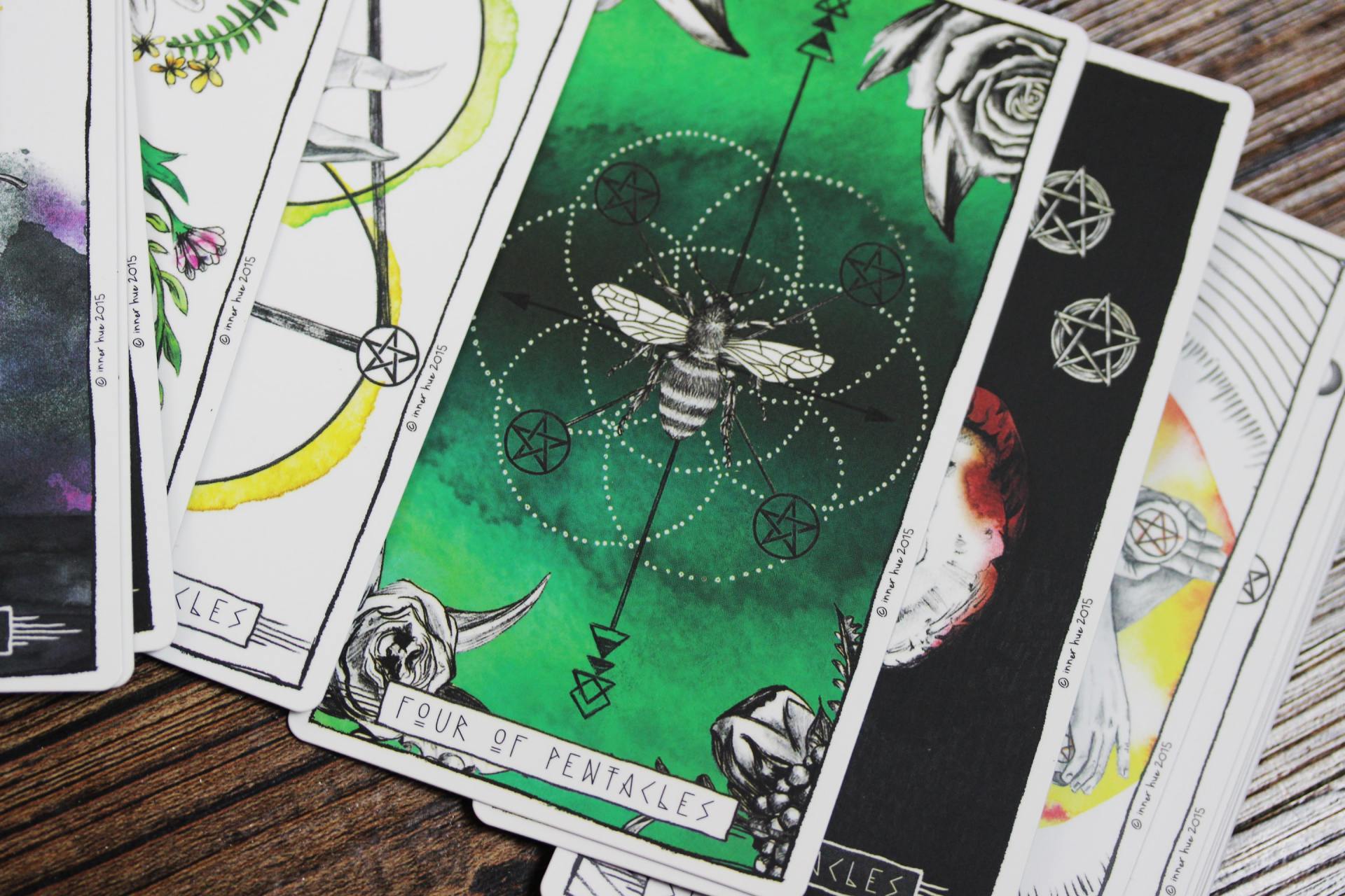 A stack of tarot cards on a wooden table with the fool tarot card on top