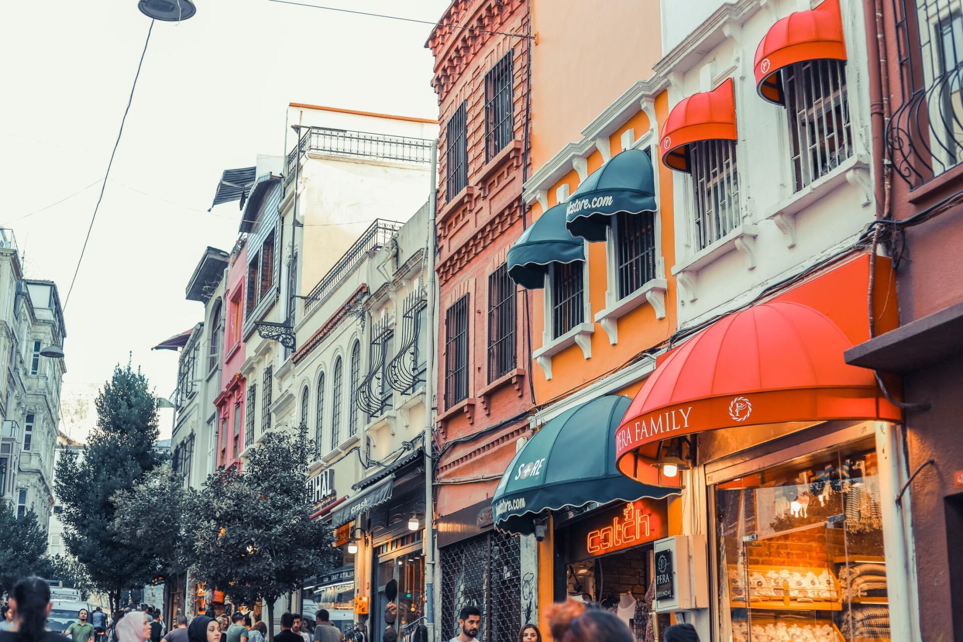 A row of buildings with awnings on the windows are lined up on a busy street.