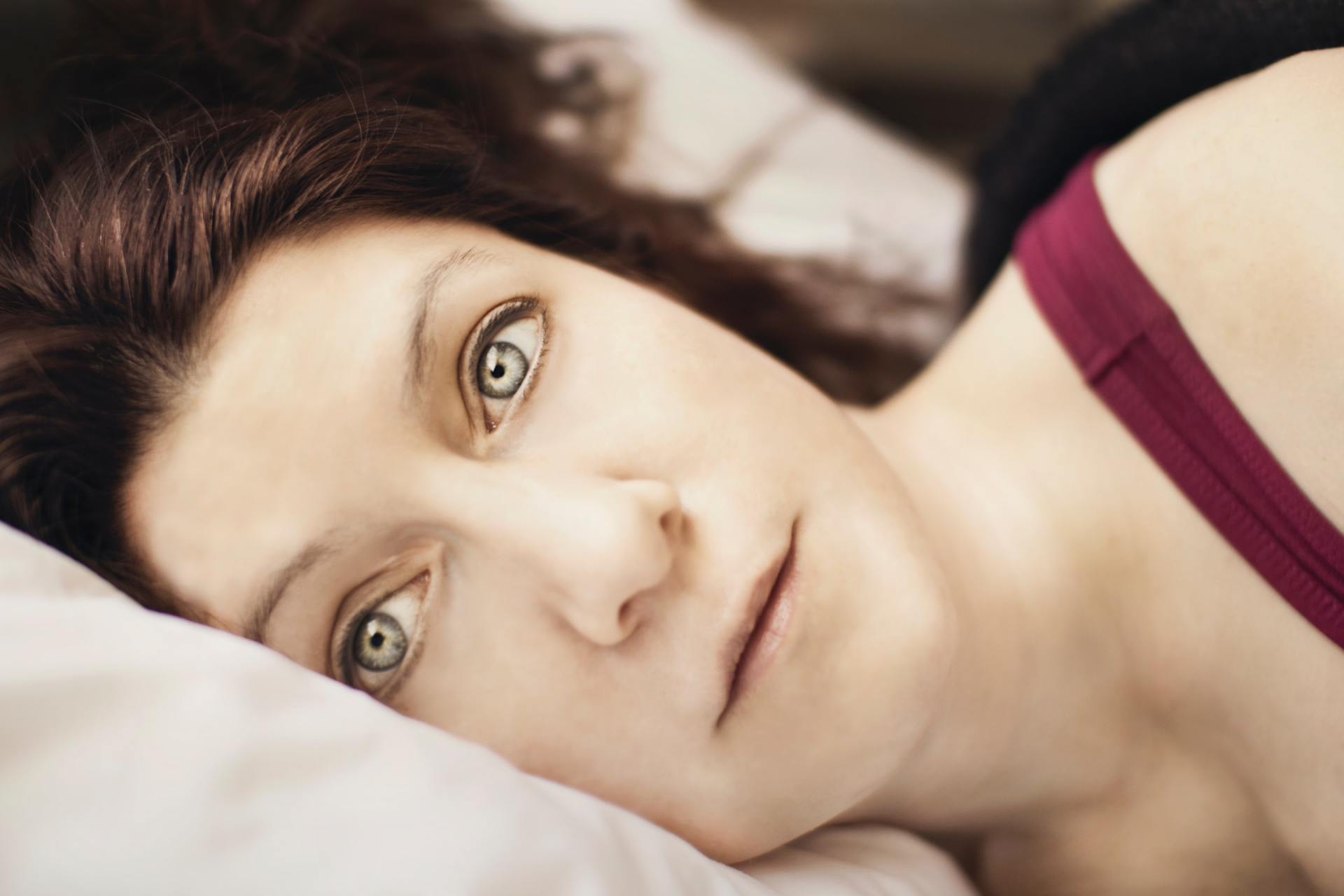 A woman is laying on a bed with her eyes closed.
