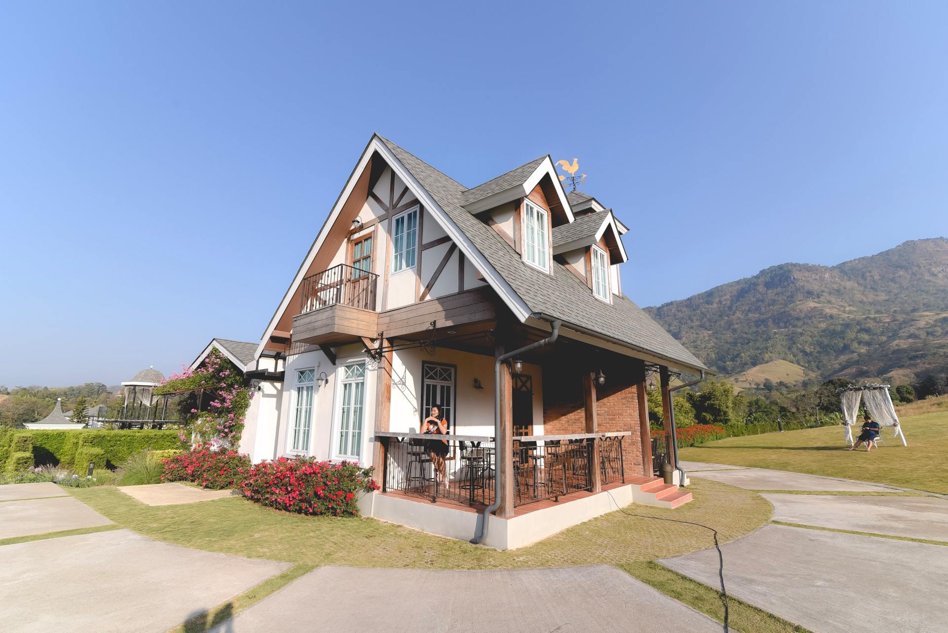 A small house with a gray roof is surrounded by mountains.